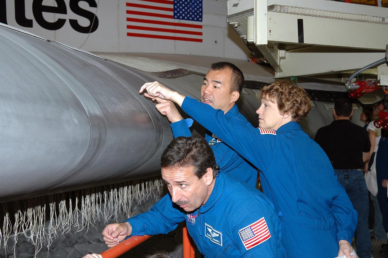 KENNEDY SPACE CENTER, FLA.  - In the Orbiter Processing Facility, STS-114 Mission Specialist Charles Camarda looks under the wing leading edge on Discovery while Mission Specialist Soichi Noguchi and Commander Eileen Collins look at an area on top.  They and other crew members are at KSC for Crew Equipment Interface Test activities. The leading edge panels of the orbiters’ wings have 22 Reinforced Carbon-Carbon panels, made entirely of carbon composite material. The molded components are approximately 0.25-inch to 0.5-inch thick. During CEIT, the crew has an opportunity to get a hands-on look at the orbiter and equipment they will be working with on the mission.  Return to Flight Mission STS-114 will carry the Multi-Purpose Logistics Module Raffaello, filled with supplies for the International Space Station, and a replacement Control Moment Gyroscope.  Launch of STS-114 has a launch window of May 12 to June 3.
