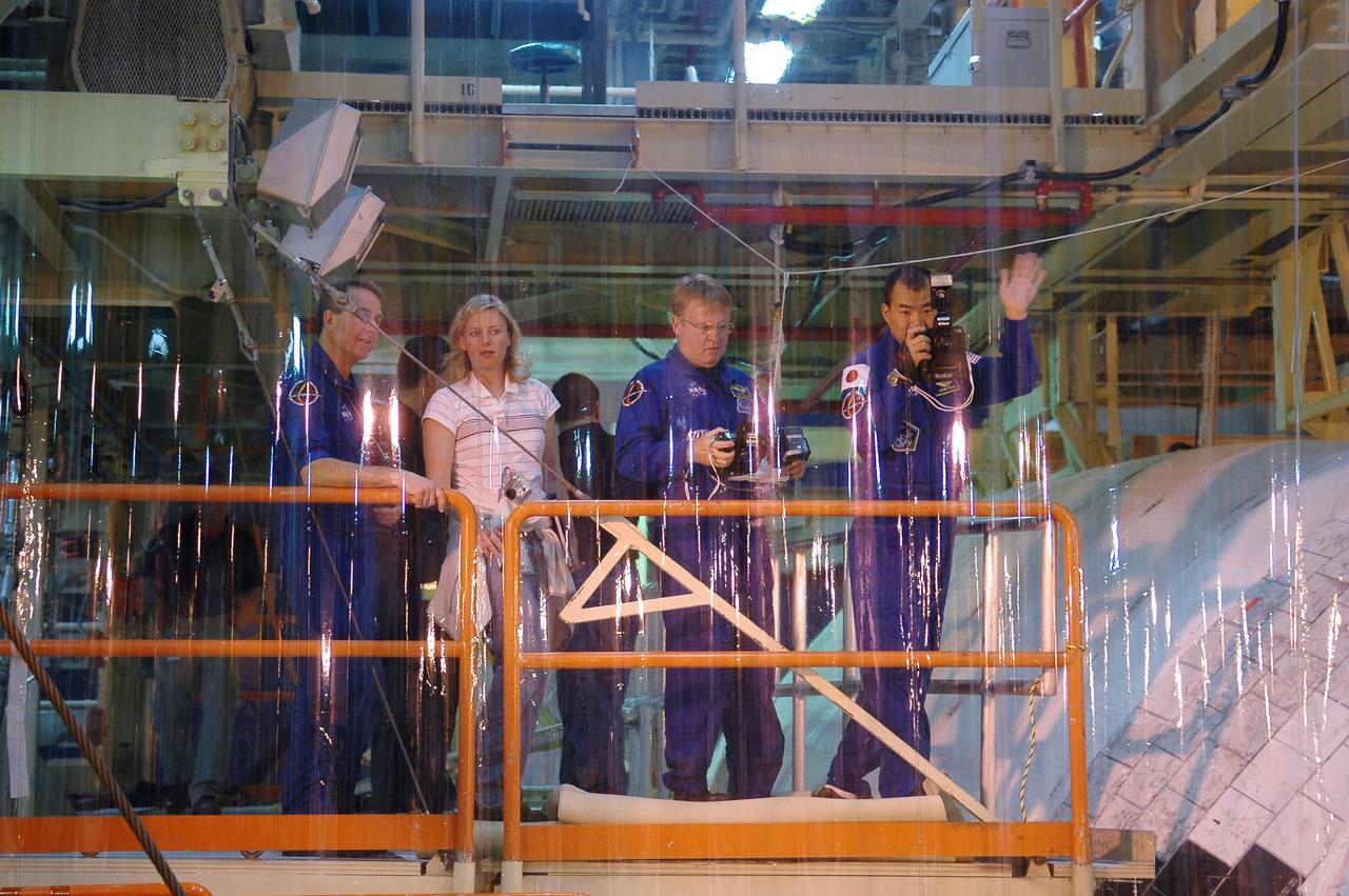 KENNEDY SPACE CENTER, FLA.  - In the Orbiter Processing Facility, STS-114 crew members behind a protective screen practice using handheld cameras as they look into Discovery’s payload bay.  At left is Mission Specialist Stephen Robinson; at right are Mission Specialists Andrew Thomas and Soichi Noguchi (with the Japanese Space Agency).  They will use the cameras during the mission.  Crew members are at KSC for Crew Equipment Interface Test activities.  During CEIT, the crew has an opportunity to get a hands-on look at the orbiter and equipment they will be working with on the mission.  Return to Flight Mission STS-114 will carry the Multi-Purpose Logistics Module Raffaello, filled with supplies for the International Space Station, and a replacement Control Moment Gyroscope.  Launch of STS-114 has a launch window of May 12 to June 3.