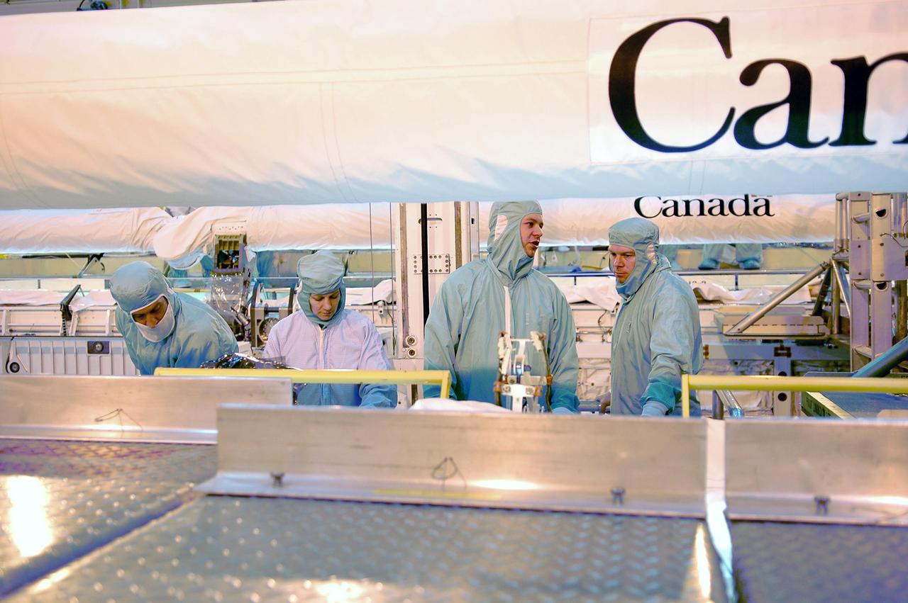 KENNEDY SPACE CENTER, FLA.  - In the Orbiter Processing Facility, STS-114 crew members look at the new Orbiter Boom Sensor System recently installed in Discovery’s payload bay.  At left are Mission Specialist Charles Camarda and Commander Eileen Collins; at right is Matt Myer, an EVA systems engineer from Johnson Space Center, and Pilot James Kelly.  Behind them can be seen the Canada robotic arm.  Crew members are at KSC for Crew Equipment Interface Test activities.  During CEIT, the crew has an opportunity to get a hands-on look at the orbiter and equipment they will be working with on the mission.  Return to Flight Mission STS-114 will carry the Multi-Purpose Logistics Module Raffaello, filled with supplies for the International Space Station, and a replacement Control Moment Gyroscope.  Launch of STS-114 has a launch window of May 12 to June 3.