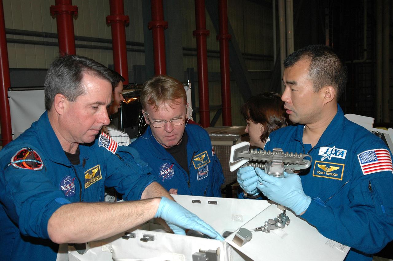 KENNEDY SPACE CENTER, FLA.  - In the Orbiter Processing Facility, members of the STS-114 crew look at tools from the Tool Stowage Assembly.  From left are Mission Specialists Stephen Robinson, Andrew Thomas and Soichi Noguchi, who is with the Japanese Space Agency.  They and other crew members are at Kennedy for Crew Equipment Interface Test activities. During CEIT, the crew has an opportunity to get a hands-on look at the payloads with which they’ll be working on orbit.  The Return to Flight mission STS-114 will carry a replacement Control Moment Gyroscope and the Multi-Purpose Logistics Module Raffaello, filled with supplies for the International Space Station.  Launch of STS-114 has a launch window of May 12 to June 3.
