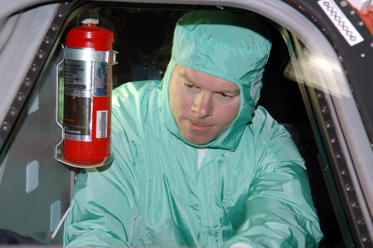 KENNEDY SPACE CENTER, FLA. - In the Orbiter Processing Facility, STS-114 Pilot James Kelly inspects the window in Discovery’s cockpit. The crew is at Kennedy for Crew Equipment Interface Test activities. During CEIT, the crew has an opportunity to get a hands-on look at the payloads with which they’ll be working on orbit. The Return to Flight mission STS-114 will carry a replacement Control Moment Gyroscope and the Multi-Purpose Logistics Module Raffaello, filled with supplies for the International Space Station. Launch of STS-114 has a launch window of May 12 to June 3.