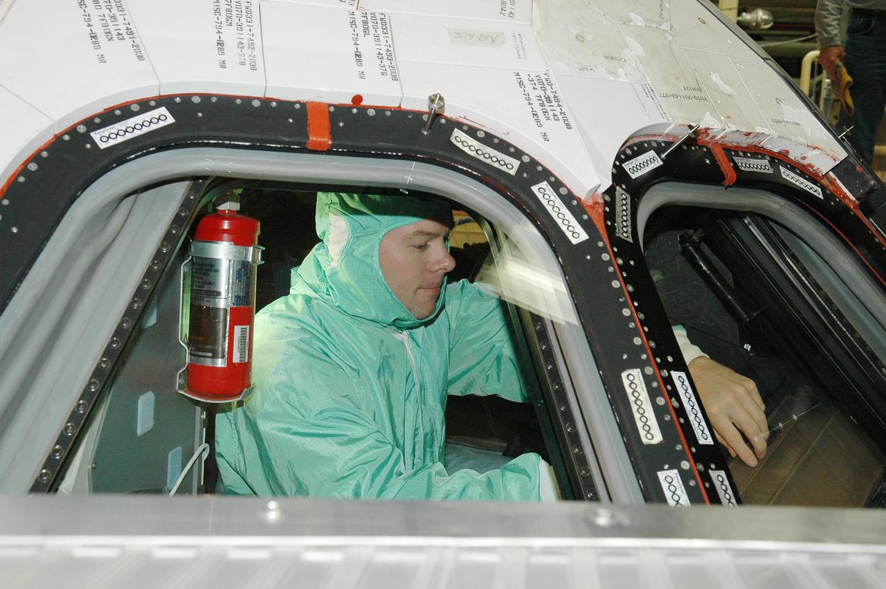 KENNEDY SPACE CENTER, FLA. - In the Orbiter Processing Facility, STS-114 Pilot James Kelly inspects the window in Discovery’s cockpit. The crew is at Kennedy for Crew Equipment Interface Test activities. During CEIT, the crew has an opportunity to get a hands-on look at the payloads with which they’ll be working on orbit. The Return to Flight mission STS-114 will carry a replacement Control Moment Gyroscope and the Multi-Purpose Logistics Module Raffaello, filled with supplies for the International Space Station. Launch of STS-114 has a launch window of May 12 to June 3.