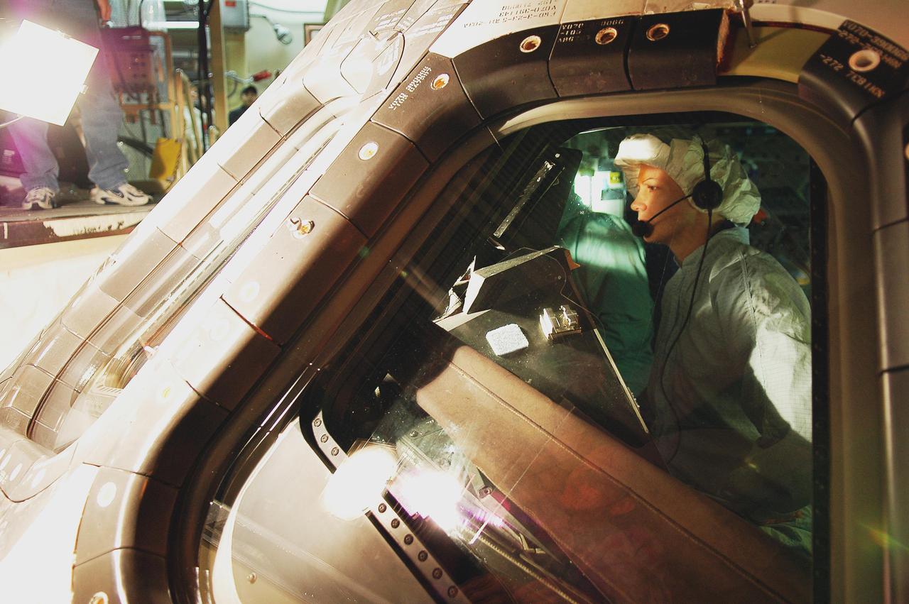 KENNEDY SPACE CENTER, FLA. - In the Orbiter Processing Facility, STS-114 Mission Commander Eileen Collins checks the window in Discovery’s cockpit. Behind her sits Pilot James Kelly. The crew is at Kennedy for Crew Equipment Interface Test activities. During CEIT, the crew has an opportunity to get a hands-on look at the payloads with which they’ll be working on orbit. The Return to Flight mission STS-114 will carry a replacement Control Moment Gyroscope and the Multi-Purpose Logistics Module Raffaello, filled with supplies for the International Space Station. Launch of STS-114 has a launch window of May 12 to June 3.