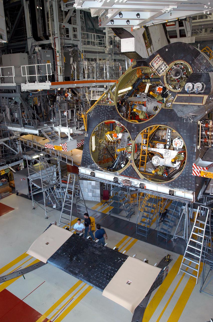 KENNEDY SPACE CENTER, FLA.  - In the Orbiter Processing Facility, workers on the floor get ready to install the body flap on the orbiter Atlantis, behind them.  The body flap is an aluminum structure consisting of ribs, spars, skin panels and a trailing edge assembly.  It thermally shields the three Space Shuttle Main Engines during entry and provides the orbiter with pitch control trim during its atmospheric flight after entry.  Atlantis is being processed for its mission, designated STS-121, this summer to the International Space Station.  The launch planning window is July 12 - August 3.
