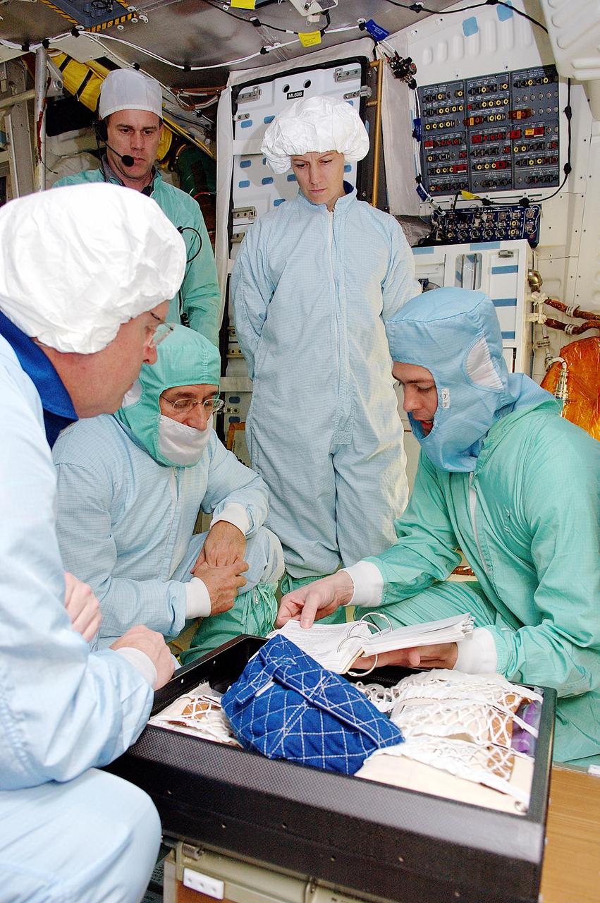 KENNEDY SPACE CENTER, FLA. - STS-114 crew members familiarize themselves with elements in the mid-body and upper deck of the orbiter Discovery, as part of Crew Equipment Interface Test (CEIT) activities. At left is Mission Specialist Andrew Thomas; kneeling in center is Mission Specialist Charles Camarda; standing in center is Commander Eileen Collins. At right is Steve Contella, an engineer with Johnson Space Center. During CEIT, the crew has an opportunity to get a hands-on look at the orbiter and equipment they will be working with on the mission. Return to Flight Mission STS-114 will carry the Multi-Purpose Logistics Module Raffaello, filled with supplies for the International Space Station, and a replacement Control Moment Gyroscope. Launch of STS-114 has a launch window of May 12 to June 3.