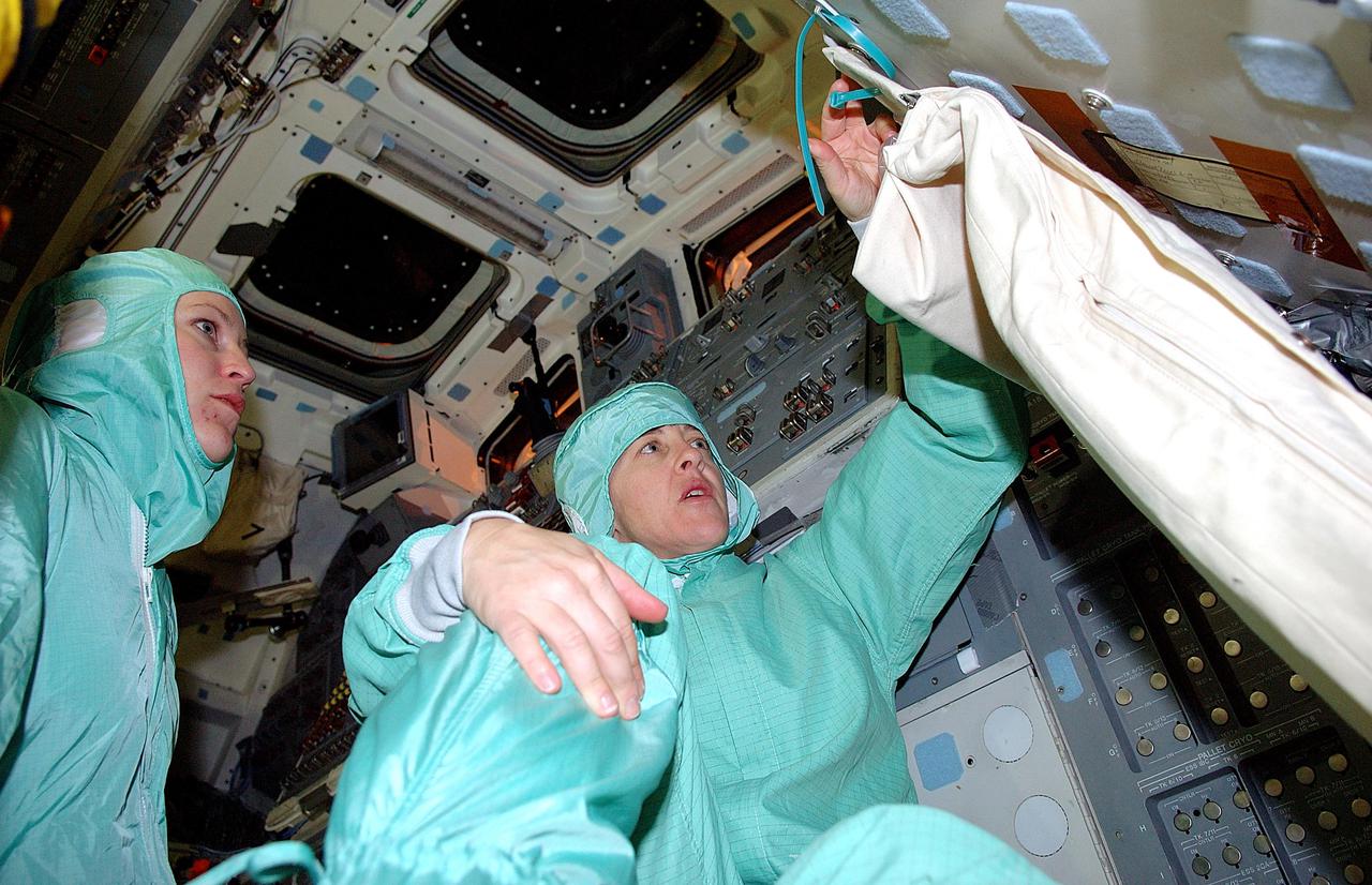 KENNEDY SPACE CENTER, FLA.  - STS-114 Mission Specialist Wendy Lawrence (right) learns about equipment inside the orbiter Discovery from Reina Winters, an engineer with Johnson Space Center.   STS-114 crew members are familiarizing themselves with elements in the mid-body and upper deck of Discovery as part of Crew Equipment Interface Test (CEIT) activities. During CEIT, the crew has an opportunity to get a hands-on look at the orbiter and equipment they will be working with on the mission.  Return to Flight Mission STS-114 will carry the Multi-Purpose Logistics Module Raffaello, filled with supplies for the International Space Station, and a replacement Control Moment Gyroscope.  Launch of STS-114 has a launch window of May 12 to June 3.
