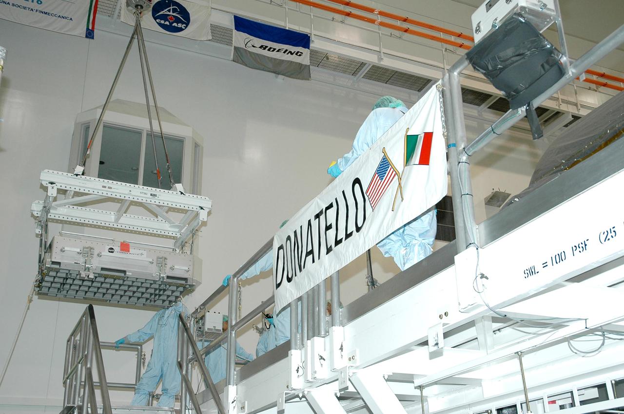 KENNEDY SPACE CENTER, FLA. - An overhead crane in the Space Station Processing Facility moves the Thermal Protection System Detailed Test Objective (DTO) box toward the Lightweight Multi-Purpose Experiment Support Structure Carrier (LMC) that is situated near the Multi-Purpose Logistics Module Donatello. The LMC and DTO will fly on Space Shuttle Discovery for mission STS-114. The DTO contains tile samples that will enable astronauts to test new on-orbit Thermal Protection System repair techniques. The launch window for mission STS-114 is May 12 to June 3.
