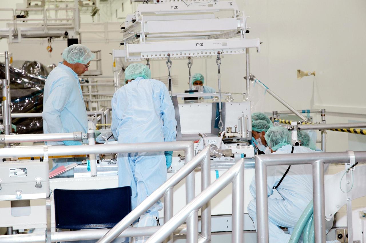 KENNEDY SPACE CENTER, FLA.  - Technicians in the Space Station Processing Facility ensure the Thermal Protection System Detailed Test Objective (DTO) box  is placed correctly on the Lightweight Multi-Purpose Experiment Support Structure Carrier (LMC).  The LMC and DTO will fly on Space Shuttle Discovery for mission STS-114. The DTO contains tile samples that will enable astronauts to test new on-orbit Thermal Protection System repair techniques.  The launch window for mission STS-114 is May 12 to June 3.