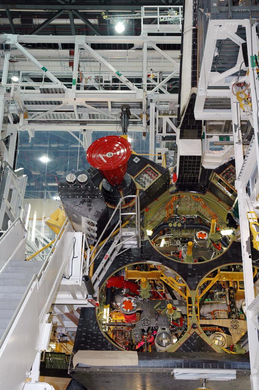 KENNEDY SPACE CENTER, FLA. - Space Shuttle Atlantis is outfitted with its left Orbital Maneuvering System (OMS) pod in Orbiter Process Facility bay 1. The Orbital Maneuvering System provides the thrust for orbit insertion, orbit circularization, orbit transfer, rendezvous, deorbit, abort to orbit and abort once around. It can provide up to 1,000 pounds of propellant to the aft reaction control system. Each pod contains one OMS engine and the hardware needed to pressurize, store and distribute the propellants to perform the velocity maneuvers. Atlantis is the designated orbiter to fly on mission STS-121. The mission has a launch window of July 12 - July 31.
