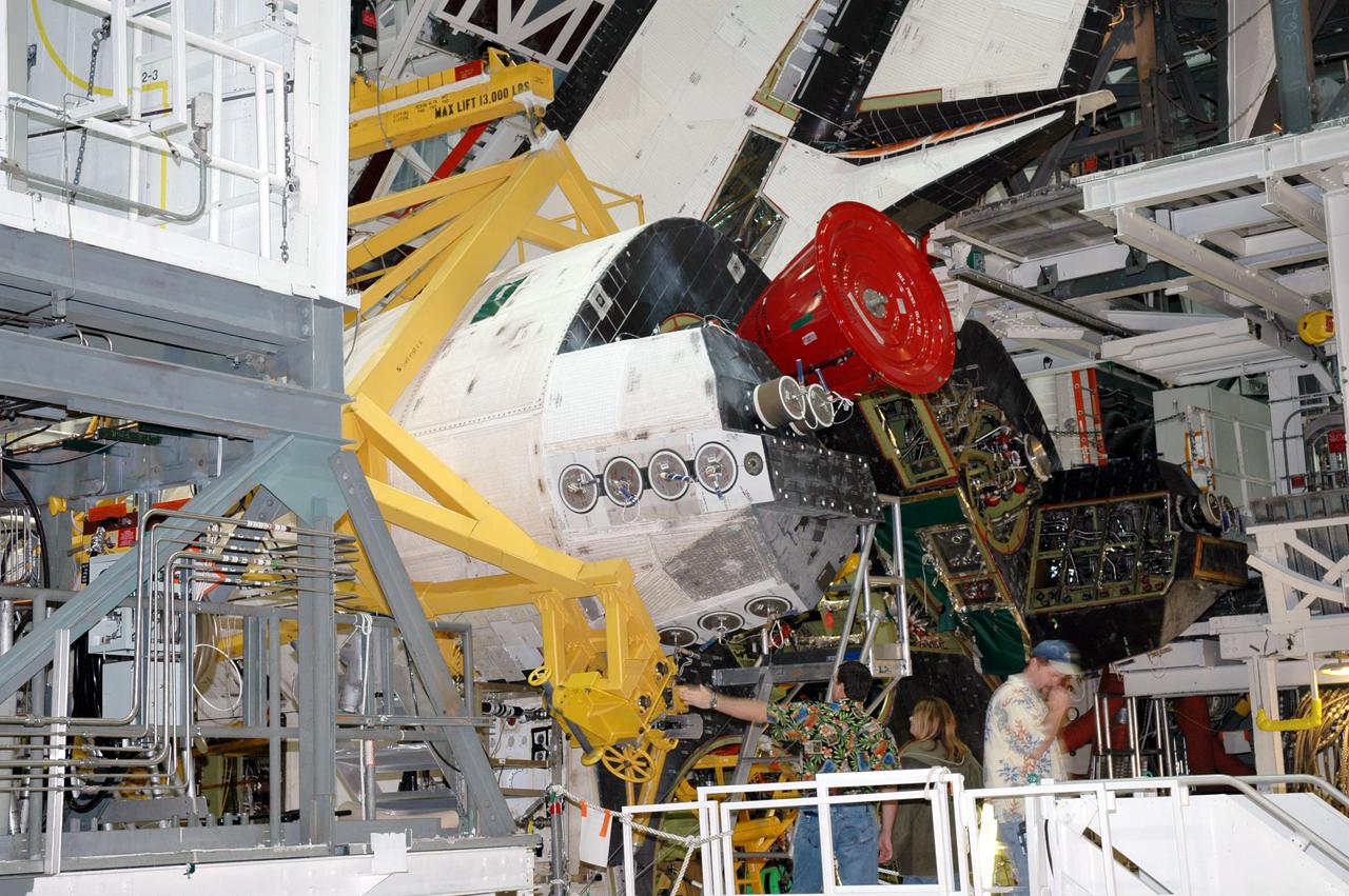 KENNEDY SPACE CENTER, FLA. - Technicians discuss the left Orbital Maneuvering System (OMS) pod installed on Space Shuttle Atlantis today in Orbiter Process Facility bay 1. The Orbital Maneuvering System provides the thrust for orbit insertion, orbit circularization, orbit transfer, rendezvous, deorbit, abort to orbit and abort once around. It can provide up to 1,000 pounds of propellant to the aft reaction control system. Each pod contains one OMS engine and the hardware needed to pressurize, store and distribute the propellants to perform the velocity maneuvers. Atlantis is the designated orbiter to fly on mission STS-121. The mission has a launch window of July 12 - July 31.