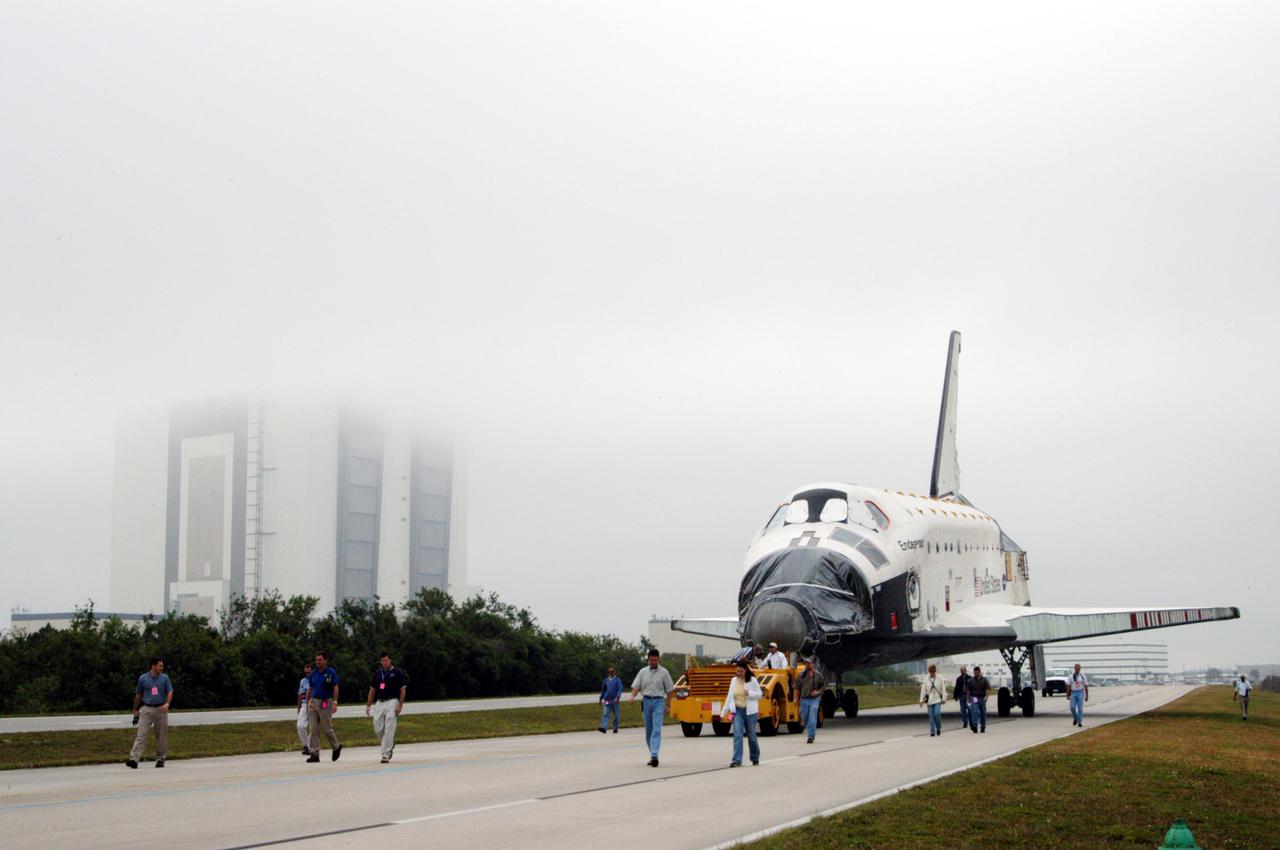 KENNEDY SPACE CENTER, FLA.  - Workers accompany the orbiter Endeavour as it rolls past the Vehicle Assembly Building on its way to Florida Space Authority’s Reusable Launch Vehicle hangar for temporary storage.  Endeavour is being moved from the Orbiter Processing Facility (OPF) to allow work to be performed in the OPF that can only be accomplished while the bay is empty.  Work scheduled in the OPF includes modifications to the bay and platform validation in the bay.   Endeavour will remain in the hangar for approximately 30 days, then return to the OPF.  Endeavour was pulled out of service in December 2003 for Orbiter Major Modification (OMM).  OMMs are scheduled at regular intervals to enhance safety and performance, infuse new technology, and, in this case, perform RTF modifications.