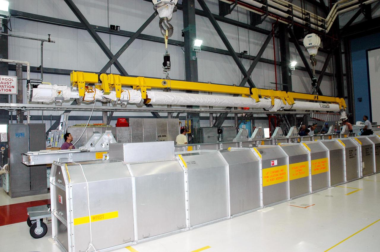 KENNEDY SPACE CENTER, FLA. - In the Orbiter Processing Facility, an overhead crane lifts the Remote Manipulator System (RMS), or Shuttle arm. The RMS is being moved for installation in Atlantis’ payload bay. The RMS includes the electromechanical arm that maneuvers a payload from the payload bay of the orbiter to its deployment position and then releases it. It can also grapple a free-flying payload, maneuver it to the payload bay of the orbiter and berth it in the orbiter. The RMS arm is 50 feet 3 inches long and 15 inches in diameter. It weighs 905 pounds, and the total system weighs 994 pounds. The RMS has six joints that correspond roughly to the joints of the human arm, with shoulder yaw and pitch joints; an elbow pitch joint; and wrist pitch, yaw and roll joints. The end effector is the unit at the end of the wrist that actually grabs, or grapples, the payload. Atlantis is the designated orbiter to fly on mission STS-121. The mission has a launch window of July 12 - July 31, 2005.