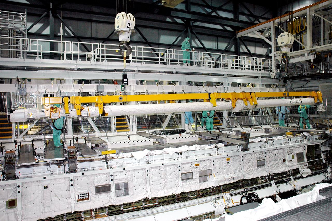 KENNEDY SPACE CENTER, FLA. - In the Orbiter Processing Facility, an overhead crane lowers the Remote Manipulator System (RMS), or Shuttle arm, toward Atlantis for installation in the payload bay. The RMS includes the electromechanical arm that maneuvers a payload from the payload bay of the orbiter to its deployment position and then releases it. It can also grapple a free-flying payload, maneuver it to the payload bay of the orbiter and berth it in the orbiter. The RMS arm is 50 feet 3 inches long and 15 inches in diameter. It weighs 905 pounds, and the total system weighs 994 pounds. The RMS has six joints that correspond roughly to the joints of the human arm, with shoulder yaw and pitch joints; an elbow pitch joint; and wrist pitch, yaw and roll joints. The end effector is the unit at the end of the wrist that actually grabs, or grapples, the payload. Atlantis is the designated orbiter to fly on mission STS-121. The mission has a launch window of July 12 - July 31, 2005.
