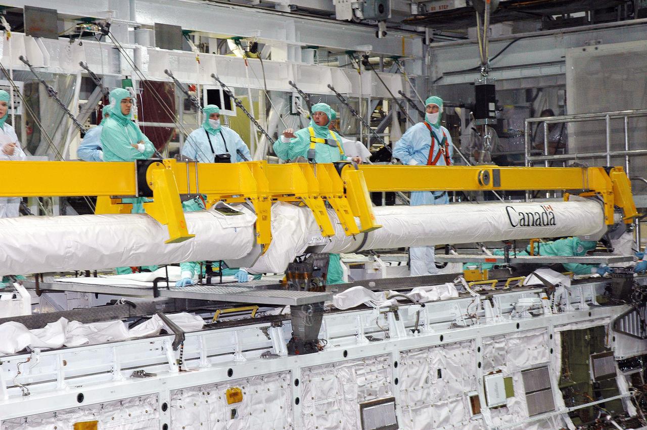 KENNEDY SPACE CENTER, FLA.  -  Workers in the Orbiter Processing Facility prepare to install the Remote Manipulator System (RMS), or Shuttle arm, in Atlantis’ payload bay.  The RMS includes the electromechanical arm that maneuvers a payload from the payload bay of the orbiter to its deployment position and then releases it. It can also grapple a free-flying payload, maneuver it to the payload bay of the orbiter and berth it in the orbiter. The RMS arm is 50 feet 3 inches long and 15 inches in diameter. It weighs 905 pounds, and the total system weighs 994 pounds. The RMS has six joints that correspond roughly to the joints of the human arm, with shoulder yaw and pitch joints; an elbow pitch joint; and wrist pitch, yaw and roll joints. The end effector is the unit at the end of the wrist that actually grabs, or grapples, the payload. Atlantis is the designated orbiter to fly on mission STS-121.  The mission has a launch window of July 12 - July 31, 2005.