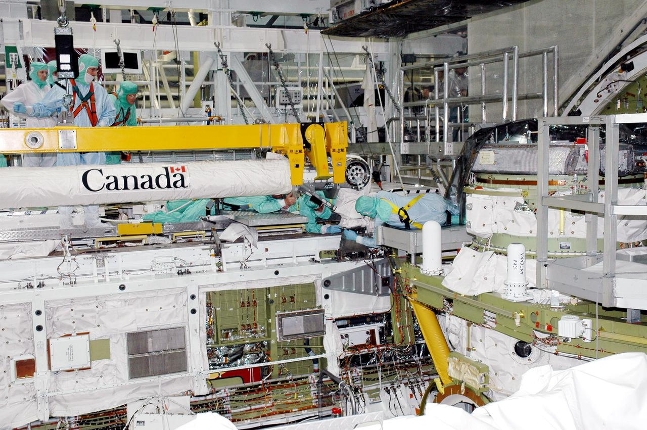 KENNEDY SPACE CENTER, FLA. - Workers in the Orbiter Processing Facility prepare the installation area for the Remote Manipulator System (RMS), or Shuttle arm, being lowered into place in Atlantis’ payload bay. The RMS includes the electromechanical arm that maneuvers a payload from the payload bay of the orbiter to its deployment position and then releases it. It can also grapple a free-flying payload, maneuver it to the payload bay of the orbiter and berth it in the orbiter. The RMS arm is 50 feet 3 inches long and 15 inches in diameter. It weighs 905 pounds, and the total system weighs 994 pounds. The RMS has six joints that correspond roughly to the joints of the human arm, with shoulder yaw and pitch joints; an elbow pitch joint; and wrist pitch, yaw and roll joints. The end effector is the unit at the end of the wrist that actually grabs, or grapples, the payload. Atlantis is the designated orbiter to fly on mission STS-121. The mission has a launch window of July 12 - July 31, 2005.
