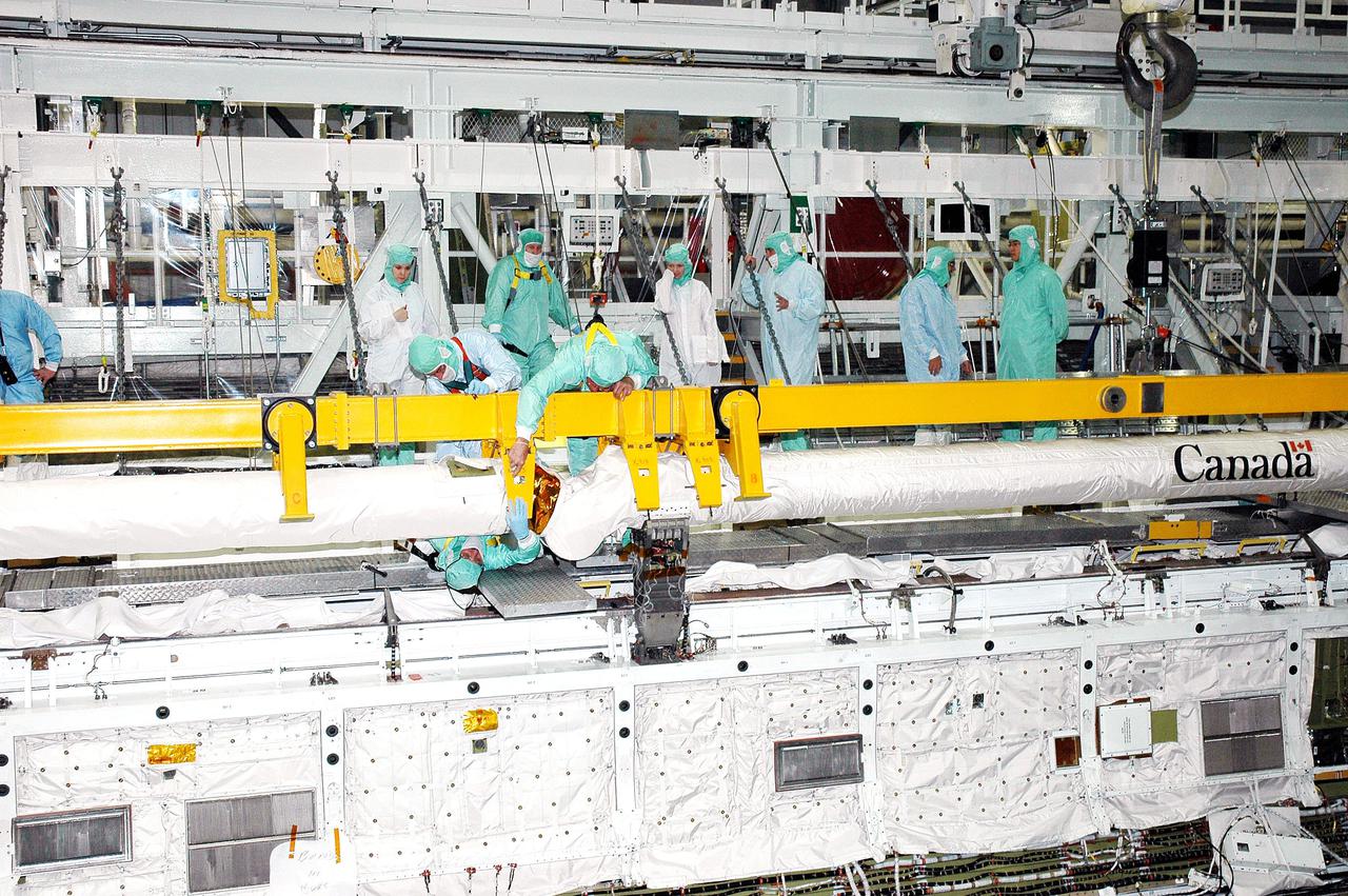 KENNEDY SPACE CENTER, FLA.  -  Workers in the Orbiter Processing Facility complete attachment of the Remote Manipulator System (RMS), or Shuttle arm, into place in Atlantis’ payload bay. The RMS includes the electromechanical arm that maneuvers a payload from the payload bay of the orbiter to its deployment position and then releases it. It can also grapple a free-flying payload, maneuver it to the payload bay of the orbiter and berth it in the orbiter. The RMS arm is 50 feet 3 inches long and 15 inches in diameter. It weighs 905 pounds, and the total system weighs 994 pounds. The RMS has six joints that correspond roughly to the joints of the human arm, with shoulder yaw and pitch joints; an elbow pitch joint; and wrist pitch, yaw and roll joints. The end effector is the unit at the end of the wrist that actually grabs, or grapples, the payload. Atlantis is the designated orbiter to fly on mission STS-121.  The mission has a launch window of July 12 - July 31, 2005.