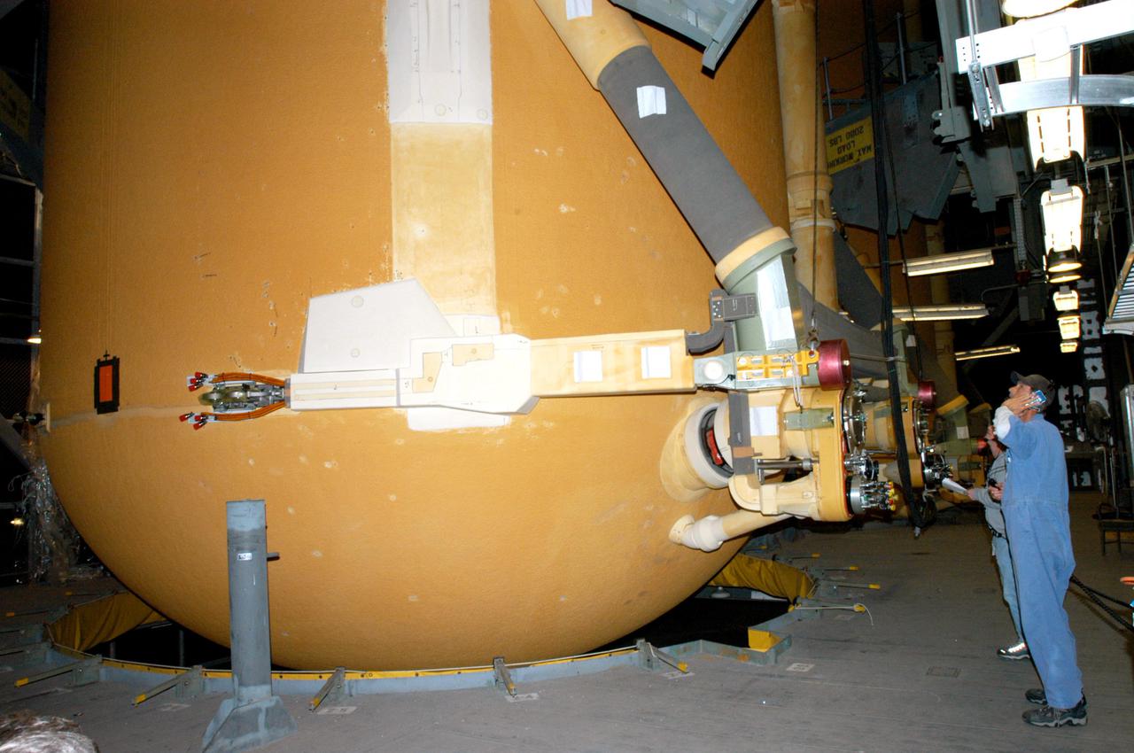 KENNEDY SPACE CENTER, FLA.  -  A technician watches as the External Tank (ET) designated to fly on Return to Flight mission STS-114 is prepared to be lifted from the checkout cell in the Vehicle Assembly Building.  It will be mated with the Solid Rocket Boosters.  The ET is recently redesigned  to meet recommendations of the Columbia Accident Investigation Board before return to flight.  Among dozens of changes is a redesigned forward bipod fitting to reduce the risk to the Space Shuttle from falling debris during ascent.  Considered a test flight, STS-114 is scheduled to launch during a window extending May 15 to June 3.  The Shuttle will carry supplies and equipment to the International Space Station.