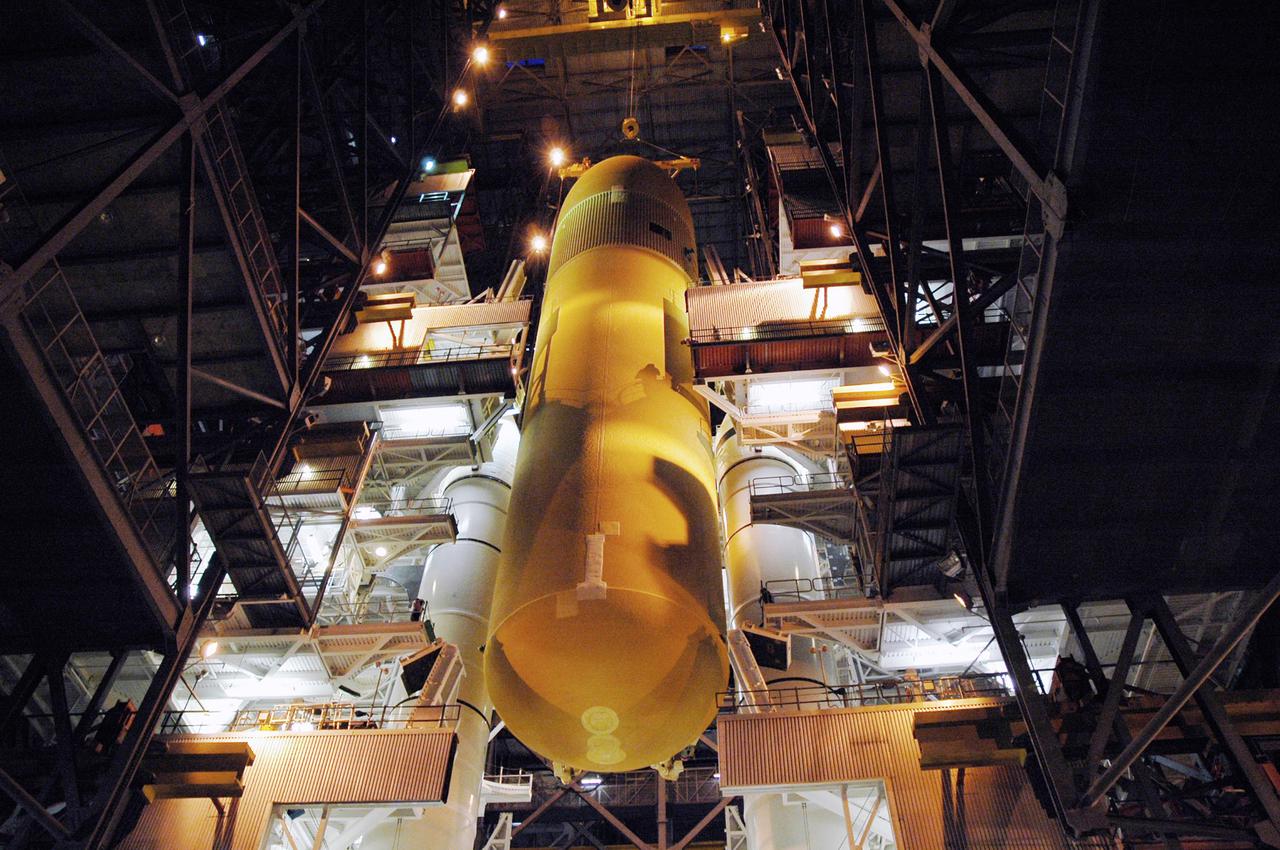 KENNEDY SPACE CENTER, FLA. - The immense size of the External Tank is captured here as a crane lowers it between the Solid Rocket Boosters (SRBs) on the Mobile Launcher Platform. The ET, designated for the Return to Flight mission STS-114, will be mated to the SRBs for launch. The 154-foot long ET is recently redesigned to meet recommendations of the Columbia Accident Investigation Board before returning to flight. Among dozens of changes is a redesigned forward bipod fitting to reduce the risk to the Space Shuttle from falling debris during ascent. Considered a test flight, STS-114 is scheduled to launch during a window extending May 15 to June 3. The Shuttle will carry supplies and equipment to the International Space Station.