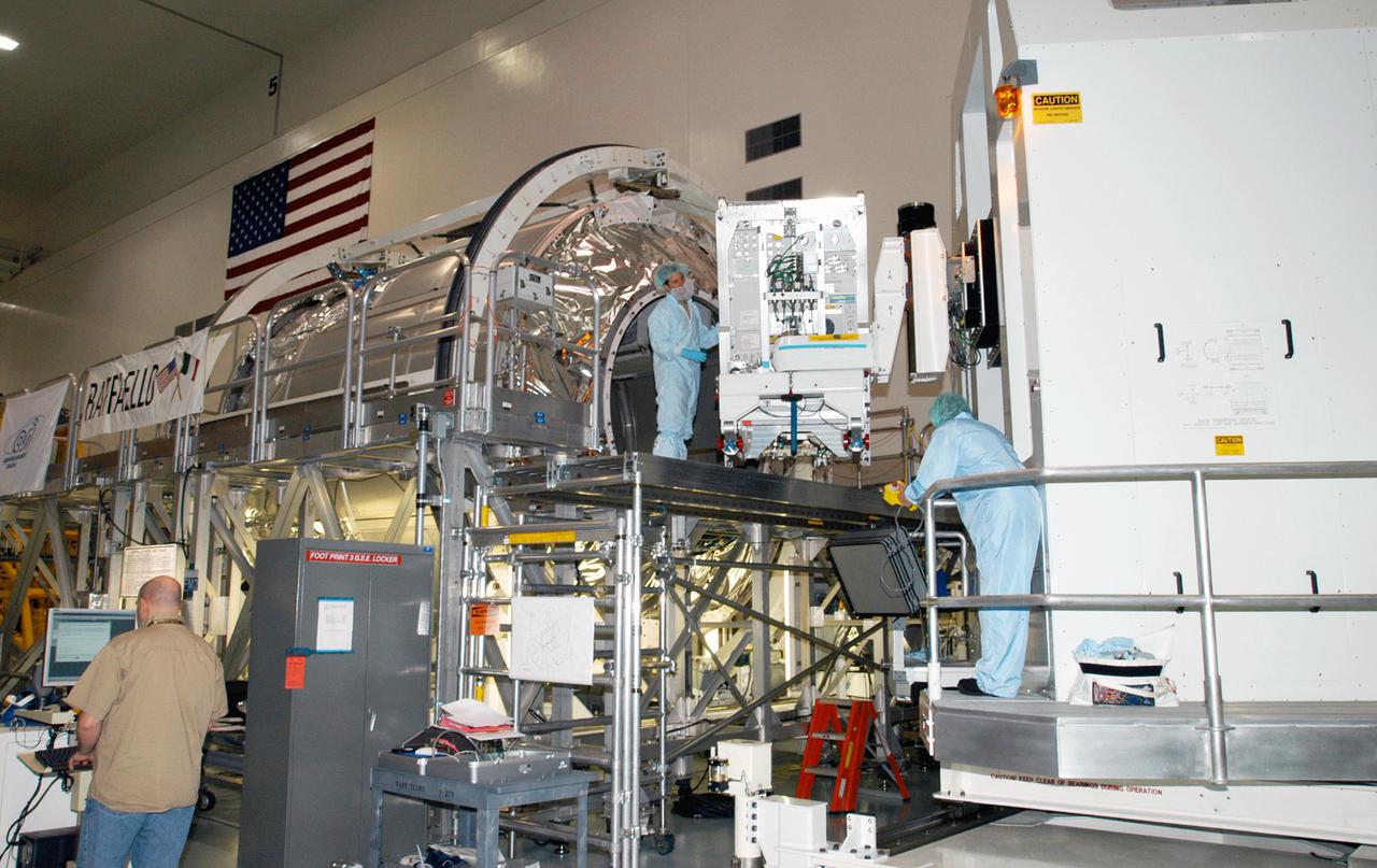 KENNEDY SPACE CENTER, FLA. - In the Space Station Processing Facility, the Rack Insertion Device moves the Human Research Facility-2 (HRF-2) science rack toward the Multi-Purpose Logistics Module Raffaello (at left) for flight on Space Shuttle Discovery’s Return to Flight mission, STS-114. The HRF-2 will deliver additional biomedical instrumentation and research capability to the International Space Station. HRF-1, installed on the U.S. Lab since May 2001, contains an ultrasound unit and gas analyzer. Both racks provide structural, power, thermal, command and data handling, and communication and tracking interfaces between the HRF biomedical instrumentation and the U.S. Laboratory, Destiny. NASA Kennedy Space Center and their prime contractor responsible for ISS element processing, The Boeing Company, prepared the rack for installation. The HRF Project is managed by NASA Johnson Space Center and implemented through contract with Lockheed Martin, Houston, Texas.