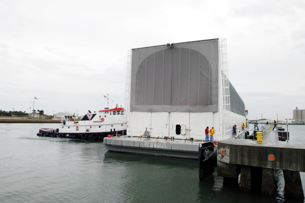 KENNEDY SPACE CENTER, FLA. - At Port Canaveral, a tug maneuvers the barge carrying a newly redesigned External Tank (ET-121) toward the dock. The tank is designated for use on Return to Flight mission STS-121. The barge was towed on a 900-mile journey at sea from the Michoud Assembly Facility in New Orleans by NASA’s Solid Rocket Booster Retrieval Ship Freedom Star. At Port Canaveral, the barge will be hooked up to tugs for the last part of the journey to the Launch Complex 39 Area Turn Basin at NASA’s Kennedy Space Center. It will then be offloaded and transported to the Vehicle Assembly Building.