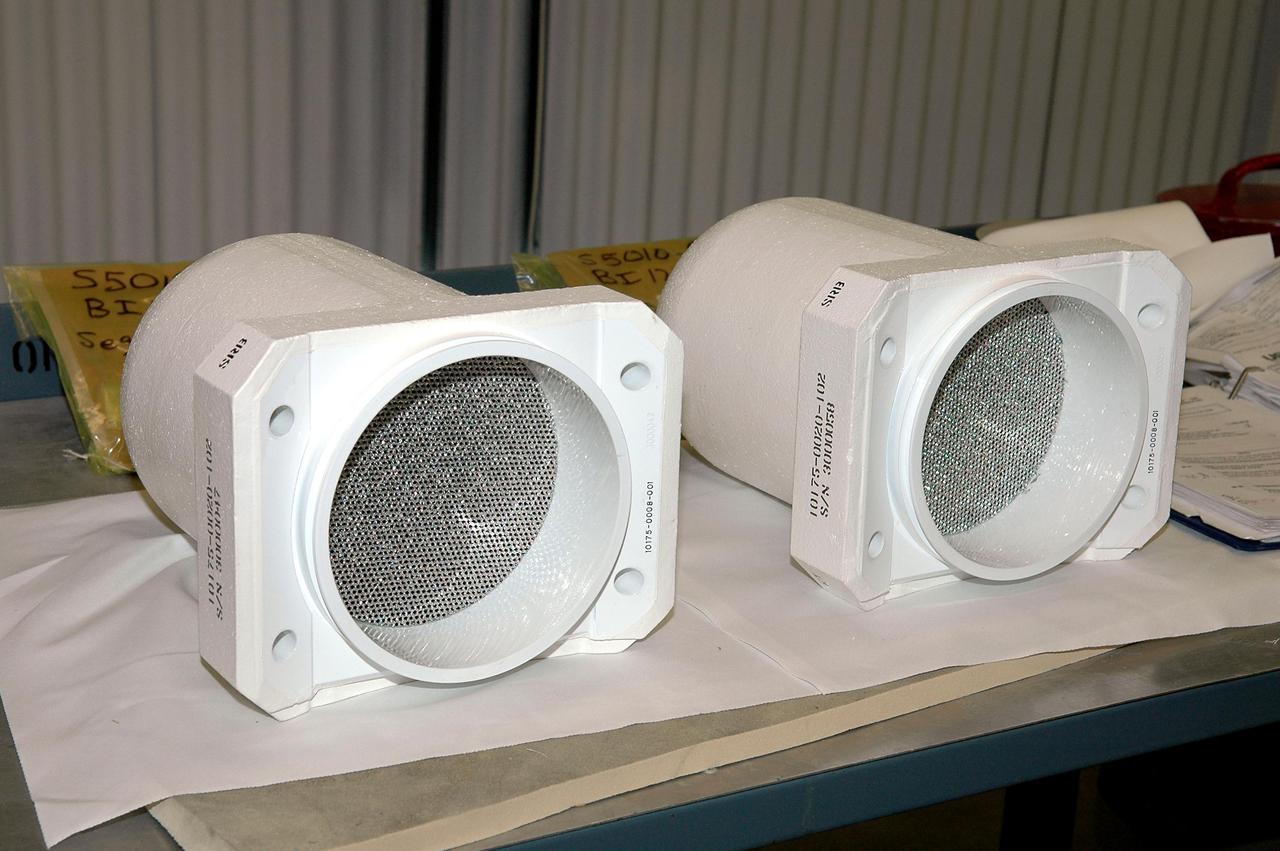 KENNEDY SPACE CENTER, FLA. - These two bolt catchers are ready for installation on orbiter Discovery’s External Tank. A bolt catcher is a vertical bolt mechanism at the forward end of the External Tank that attaches each booster to the tank. At approximately two minutes into launch, SRB separation begins when pyrotechnic devices fire to break the 25-inch, 62-pound steel bolts. One half of the bolt is caught in canister-like 'bolt catchers' located on the tank; the other half remains with the boosters. Discovery is flying with a modified bolt catcher, which was upgraded from a two-piece welded design to a one-piece, machine-made design as part of NASA's effort to return to safe, reliable spaceflight. Eliminating the weld makes a structurally stronger bolt catcher design. Though the bolt catcher is mounted on the External Tank, it is considered part of the Solid Rocket Booster element design. It is built by Summa Technologies, Inc. in Huntsville, Ala., insulated at Lockheed Martin’s Michoud Assembly Facility in New Orleans, and installed on the External Tank at KSC.