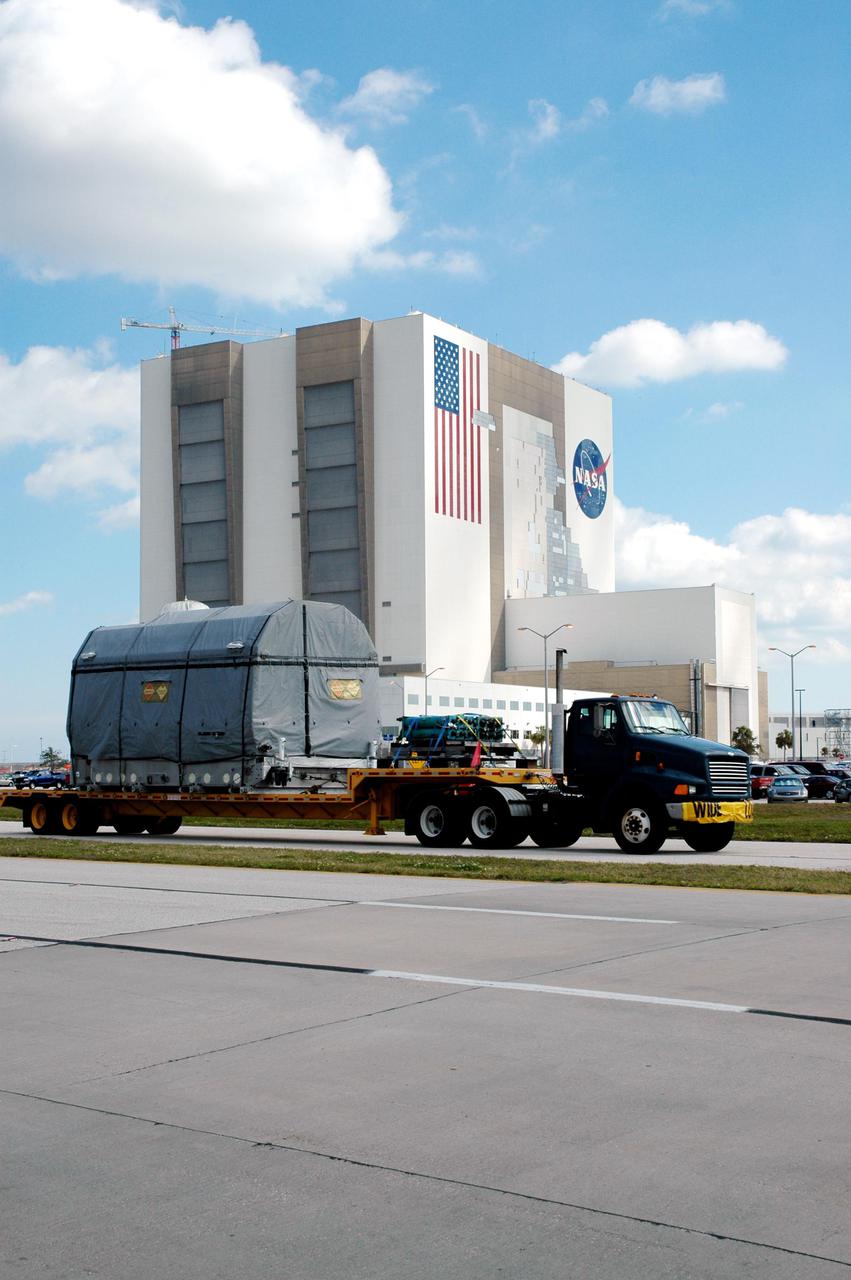 KENNEDY SPACE CENTER, FLA.  - The latest Geostationary Operational Environmental Satellite (GOES) developed by NASA for the National Oceanic and Atmospheric Administration (NOAA) travels past the Vehicle Assembly Building at KSC.  The satellite is being transported to Astrotech in Titusville, Fla., where final testing of the imaging system, instrumentation, communications and power systems will be performed over the next two months by Boeing Satellite Systems.  The satellite arrived earlier at KSC’s Shuttle Landing Facility aboard a C17 military cargo aircraft. Called GOES-N, the satellite is targeted to launch May 4 onboard a Boeing expendable launch vehicle Delta IV (4,2).  Once in orbit GOES-N will be designated GOES-13 and will complete checkout and be placed in on-orbit storage as a replacement for an older GOES satellite.