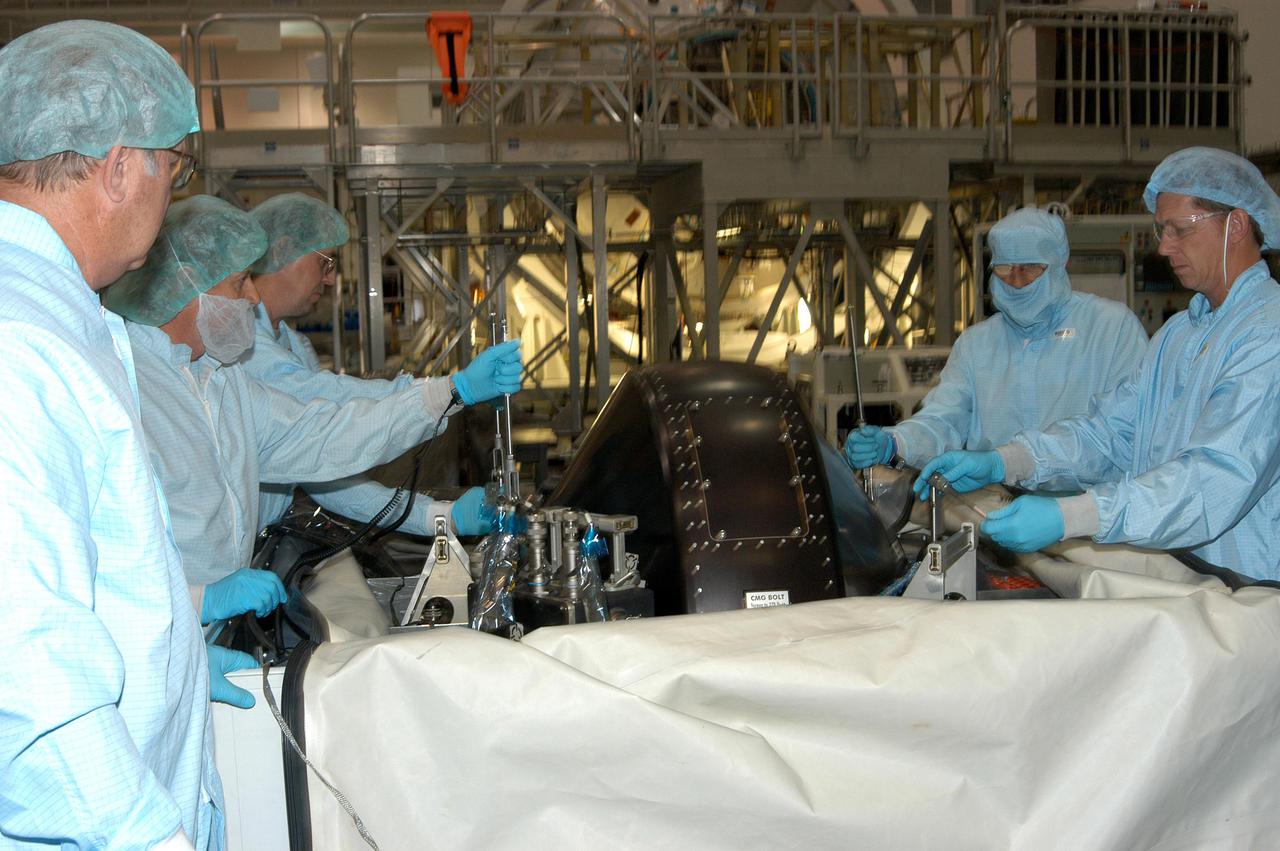 KENNEDY SPACE CENTER, FLA.  - In the Space Station Processing Facility, workers remove the protective cover from the Control Moment Gyroscope (CMG), which will be delivered to the International Space Station on Mission STS-114 aboard Space Shuttle Discovery to replace one that has failed.  CMGs are critical to ISS operation, keeping the outpost properly oriented toward the Sun without the use of rocket fuel.  Four CMGs are mounted inside a truss that extends upward from the Unity module’s zenith port. The Z1 truss, attached to the ISS during Mission STS-92 in October 2000, also carries the station’s main solar arrays.  The launch window for Discovery is May 15 to June 3, 2005.