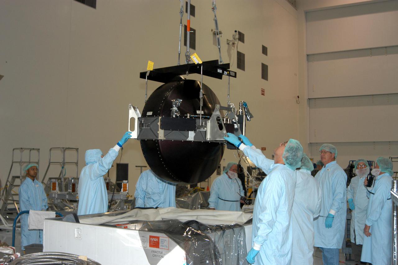 KENNEDY SPACE CENTER, FLA. - In the Space Station Processing Facility, workers help as a crane lifts the Control Moment Gyroscope (CMG) out of its shipping container. The CMG will be delivered to the International Space Station on Mission STS-114 aboard Space Shuttle Discovery to replace one that has failed. CMGs are critical to ISS operation, keeping the outpost properly oriented toward the Sun without the use of rocket fuel. Four CMGs are mounted inside a truss that extends upward from the Unity module’s zenith port. The Z1 truss, attached to the ISS during Mission STS-92 in October 2000, also carries the station’s main solar arrays. The launch window for Discovery is May 15 to June 3, 2005.