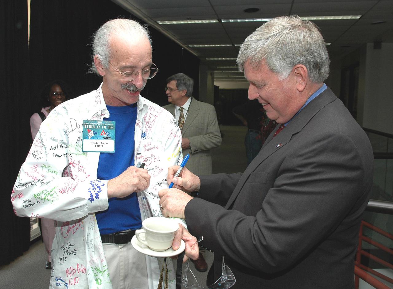 KENNEDY SPACE CENTER, FLA.  - At the 2005 FIRST Robotics Regional Competition held at the University of Central Florida March 10-12, Center Director Jim Kennedy (right) autographs the shirt of Dr. Woodie Flowers, who is a national advisor and co-founder of  FIRST.  Dr. Flowers is the Pappalardo Professor of Mechanical Engineering at the Massachusetts Institute of Technology.