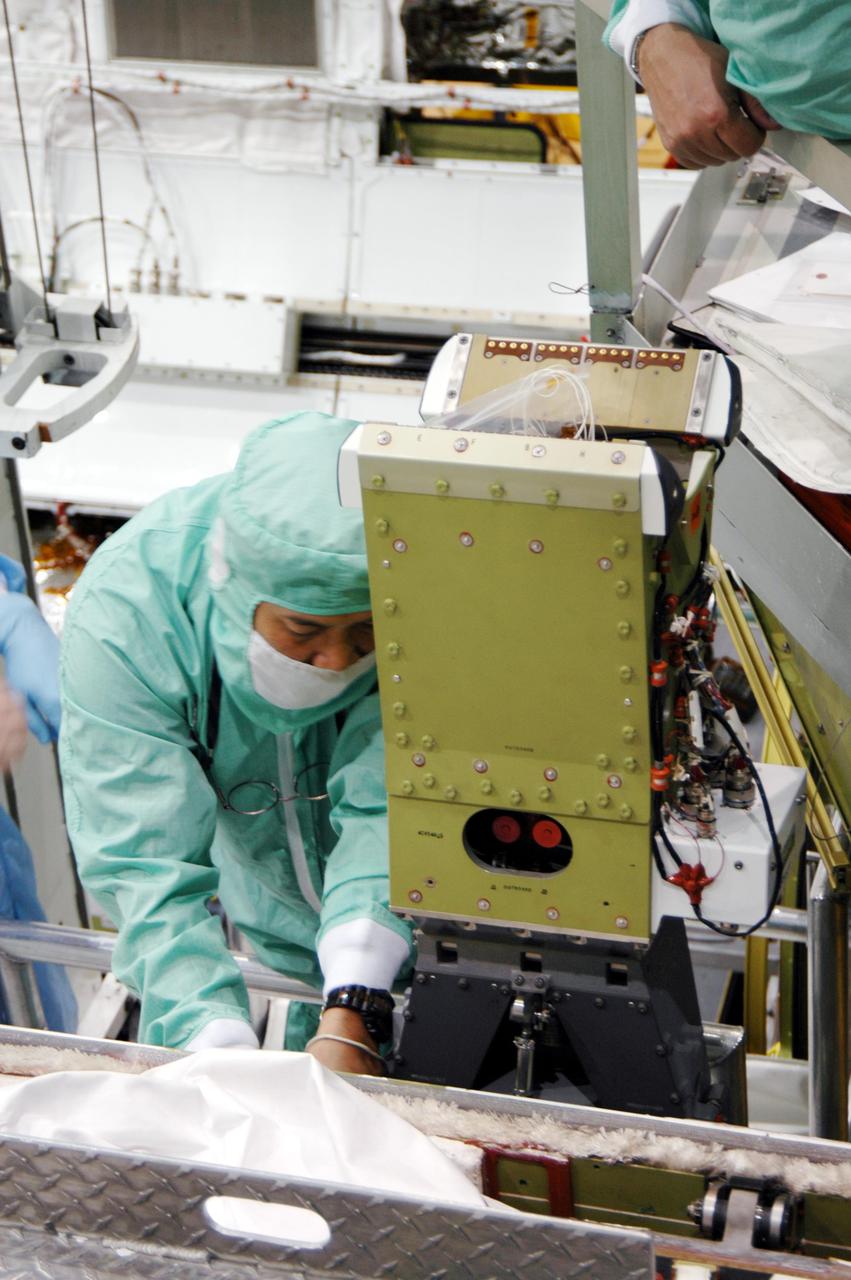 KENNEDY SPACE CENTER, FLA. - In the Orbiter Processing Facility at NASA’s Kennedy Space Center, technicians check the installation of the pedestal of the Manipulator Positioning Mechanism (MPM) on the starboard side of Atlantis’ payload bay. The MPM will hold the 50-foot-long Orbiter Boom Sensor System (OBSS) that will attach to the Remote Manipulator System, or Shuttle robotic arm. The OBSS is one of the new safety measures for Return to Flight, equipping the orbiter with cameras and laser systems to inspect the Shuttle's Thermal Protection System while in space. Atlantis is scheduled to fly on Return to Flight mission STS-121, which has a launch window of July 12 to July 31, 2005.