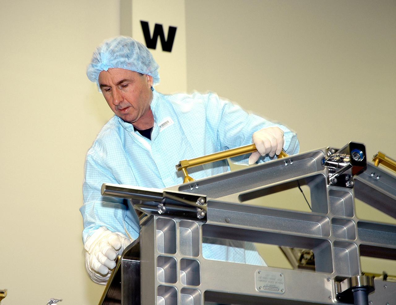 KENNEDY SPACE CENTER, FLA. - During Crew Equipment Interface Test (CEIT) at SPACEHAB in Cape Canaveral, Fla., STS-114 Mission Specialist Stephen Robinson inspects External Stowage Platform-2 (ESP2). As payload on Space Shuttle Discovery’s Return to Flight mission, the ESP2 will carry replacement parts, known as orbital replacement units (ORU) to the International Space Station. The platform will be deployed and attached to the Station’s airlock and will be used as a permanent spare parts facility. The launch window for STS-114 is May 15 to June 3, 2005. During CEIT in the Space Station Processing Facility, the crew also inspected the resupply stowage racks installed in the Italian-built Multi-Purpose Logistics Module Raffaello and performed tool and equipment interface checks with the Thermal Protection System (TPS) repair sample box, and the Control Moment Gyroscope (CMG) in preparation for the mission’s three scheduled spacewalks. The seven-member crew will fly to the Space Station primarily to evaluate procedures for flight safety, including Shuttle inspection and repair techniques.