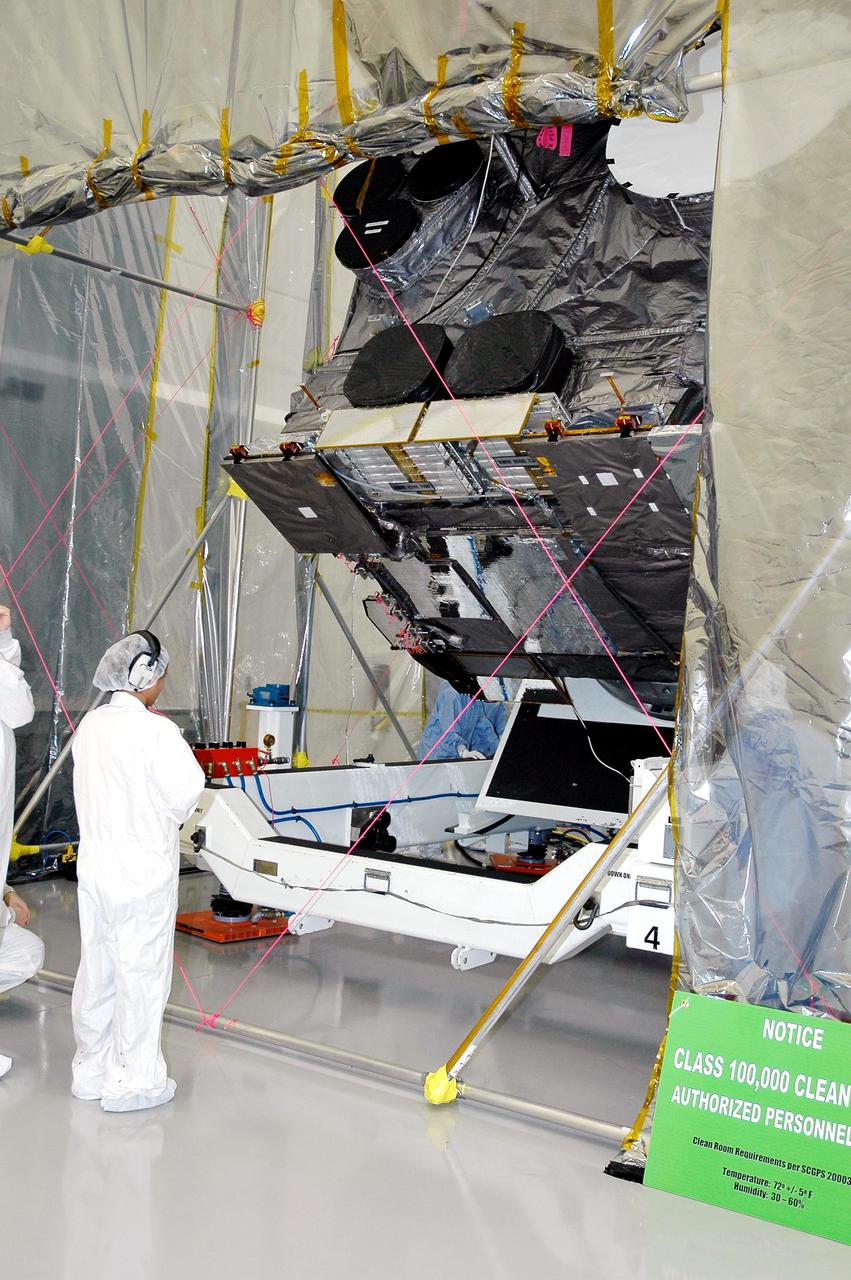 KENNEDY SPACE CENTER, FLA. - At Astrotech in Titusville, Fla., technicians closely check the progress of the rotation of the GOES-N satellite. Since its arrival on March 11, the satellite has been undergoing final testing by Boeing Satellite Systems of the imaging system, instrumentation, communications and power systems. Geostationary Operational Environmental Satellites (GOES) are sponsored by the NASA’s Goddard Space Flight Center and the National Oceanic and Atmospheric Administration. GOES-N is targeted to launch May 4 onboard a Boeing expendable launch vehicle Delta IV (4,2) with a 3-burn second stage operation. Once in orbit GOES-N will be designated GOES-13 and will complete checkout and be placed in on-orbit storage as a replacement for an older GOES satellite. GOES-N is the first in the next series of GOES satellites, N-P. The multi-mission GOES series N-P will be a vital contributor to weather, solar and space operations and science. The GOES N-P series will aid activities ranging from severe storm warnings to resource management and advances in science.