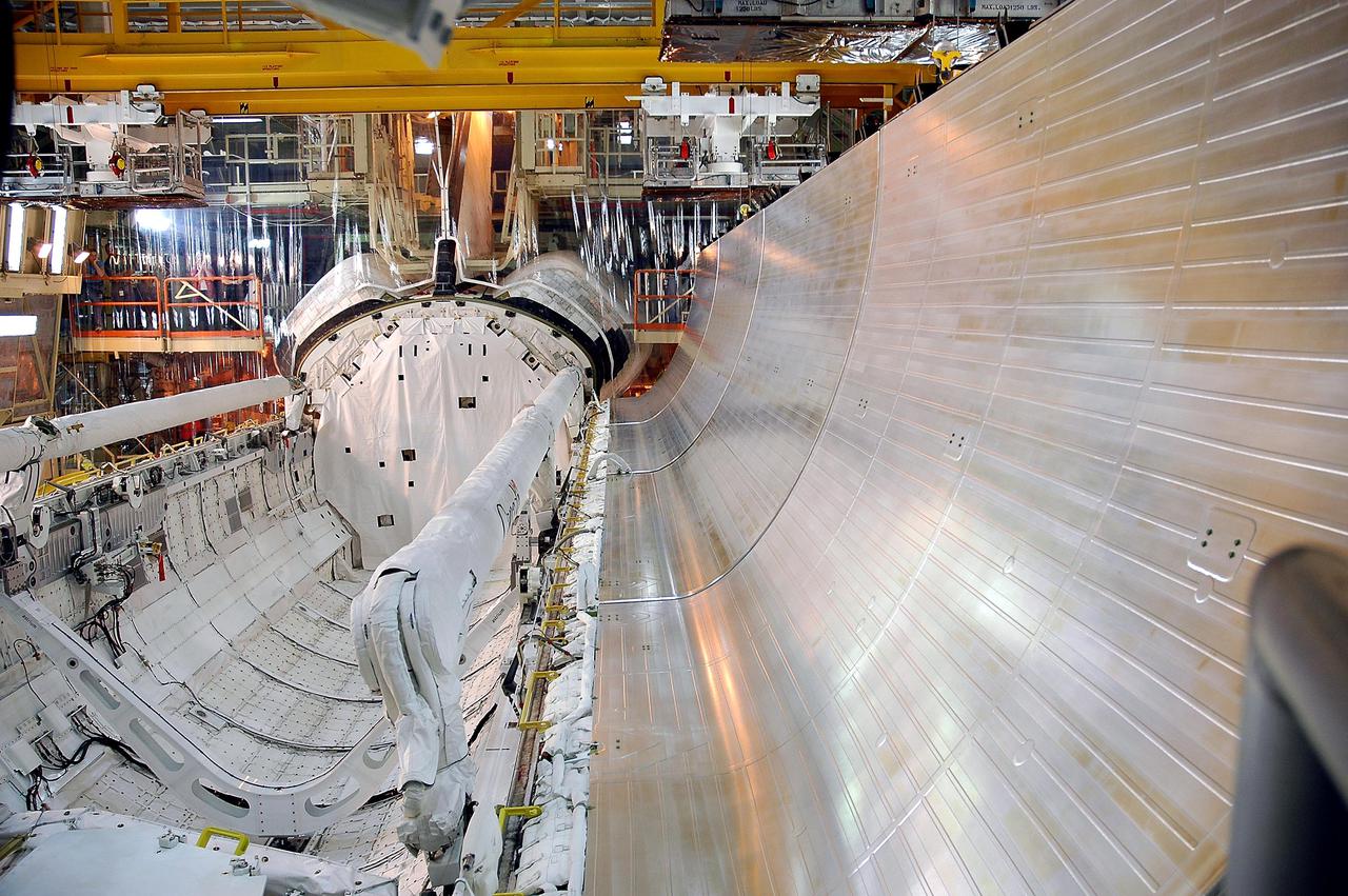 KENNEDY SPACE CENTER, FLA. - Inside Inside the Orbiter Processing Facility bay 3 at NASA’s Kennedy Space Center, one of the orbiter Discovery’s payload bay doors begins closing. Seen in the center and at left (starboard side) are the new Orbiter Boom Sensor System (OBSS) and the Remote Manipulator System (RMS), both Canadian-built. The OBSS is one of the new safety measures for Return to Flight, equipping the orbiter with cameras and laser systems to inspect the Shuttle's Thermal Protection System while in space. It attaches to the RMS. After door closure, Discovery will roll over to the Vehicle Assembly Building (VAB). Once arriving in the VAB, a sling will be attached to Discovery and the vehicle will be lifted up and lowered between its twin Solid Rocket Boosters and mated, or attached, to its redesigned External Tank. Once mated, the fully assembled Space Shuttle stack will undergo final closeouts including installation of the new digital camera in the orbiter, electrical and mechanical attachments, umbilical checks, and the interface verification test. Discovery is slated to fly mission STS-114. The launch planning window is May 15 to June 3, 2005.