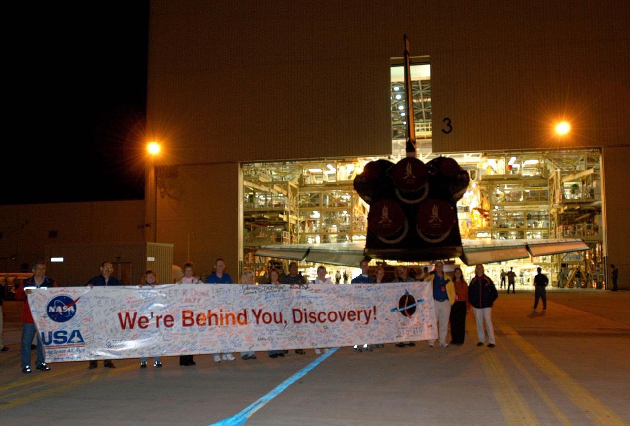KENNEDY SPACE CENTER, FLA. - Workers show their support as the orbiter Discovery slowly rolls out of the Orbiter Processing Facility bay 3 to begin its transfer to the Vehicle Assembly Building (VAB). First motion was at 1:29 a.m. EST. Inside the VAB, Discovery will be mated to the External Tank_Solid Rocket Booster assembly for Return to Flight mission STS-114. After all umbilicals have been connected, workers will perform an electrical and mechanical verification of the mated interfaces to verify all critical vehicle connections. A Space Shuttle interface test is performed to verify vehicle interfaces and vehicle-to-ground interfaces. The launch processing system is used to control and monitor orbiter systems as required. Space Shuttle Discovery will roll out to Launch Pad 39B approximately one week after the rollover to the VAB. The launch window for mission STS-114 is May 15 to June 3.