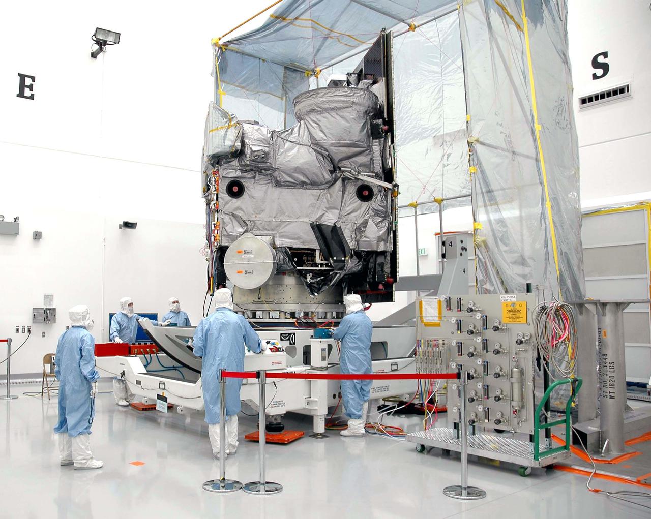 KENNEDY SPACE CENTER, FLA. - At Astrotech in Titusville, Fla., Boeing technicians check the position of the GOES-N satellite after its rotation to a vertical position. The solar panel is now behind it on the right. Since its arrival on March 11, the satellite has been undergoing final testing by Boeing Satellite Systems of the imaging system, instrumentation, communications and power systems. Geostationary Operational Environmental Satellites (GOES) are sponsored by NASA’s Goddard Space Flight Center and the National Oceanic and Atmospheric Administration. GOES-N is targeted to launch May 4 onboard a Boeing expendable launch vehicle Delta IV (4,2) with a 3-burn second stage operation.