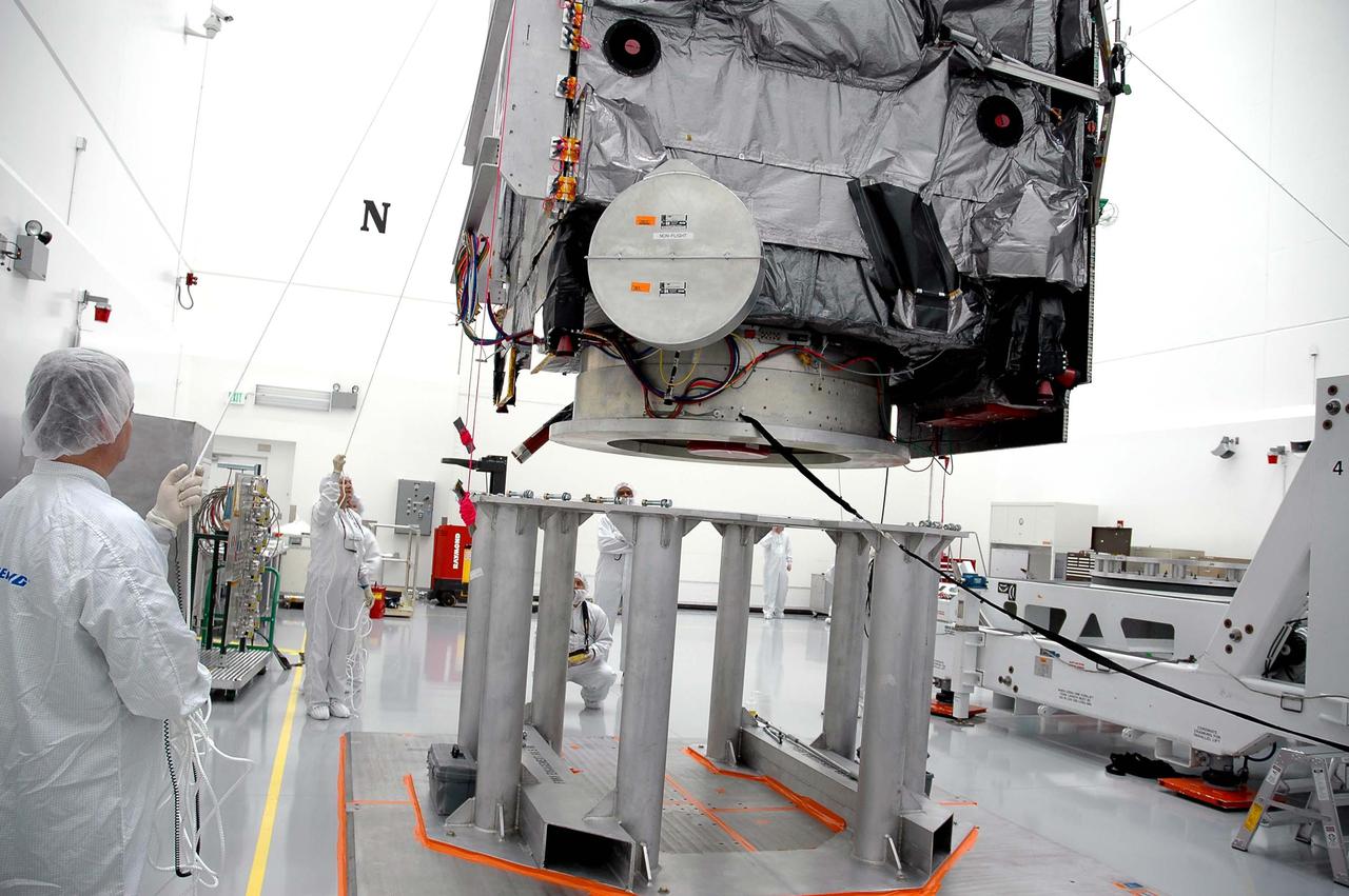 KENNEDY SPACE CENTER, FLA. - Astrotech in Titusville, Fla., Boeing technicians observe the careful lowering of the GOES-N satellite onto a work stand. Since its arrival on March 11, the satellite has been undergoing final testing by Boeing Satellite Systems of the imaging system, instrumentation, communications and power systems. Geostationary Operational Environmental Satellites (GOES) are sponsored by NASA’s Goddard Space Flight Center and the National Oceanic and Atmospheric Administration. GOES-N is targeted to launch May 4 onboard a Boeing expendable launch vehicle Delta IV (4,2) with a 3-burn second stage operation.