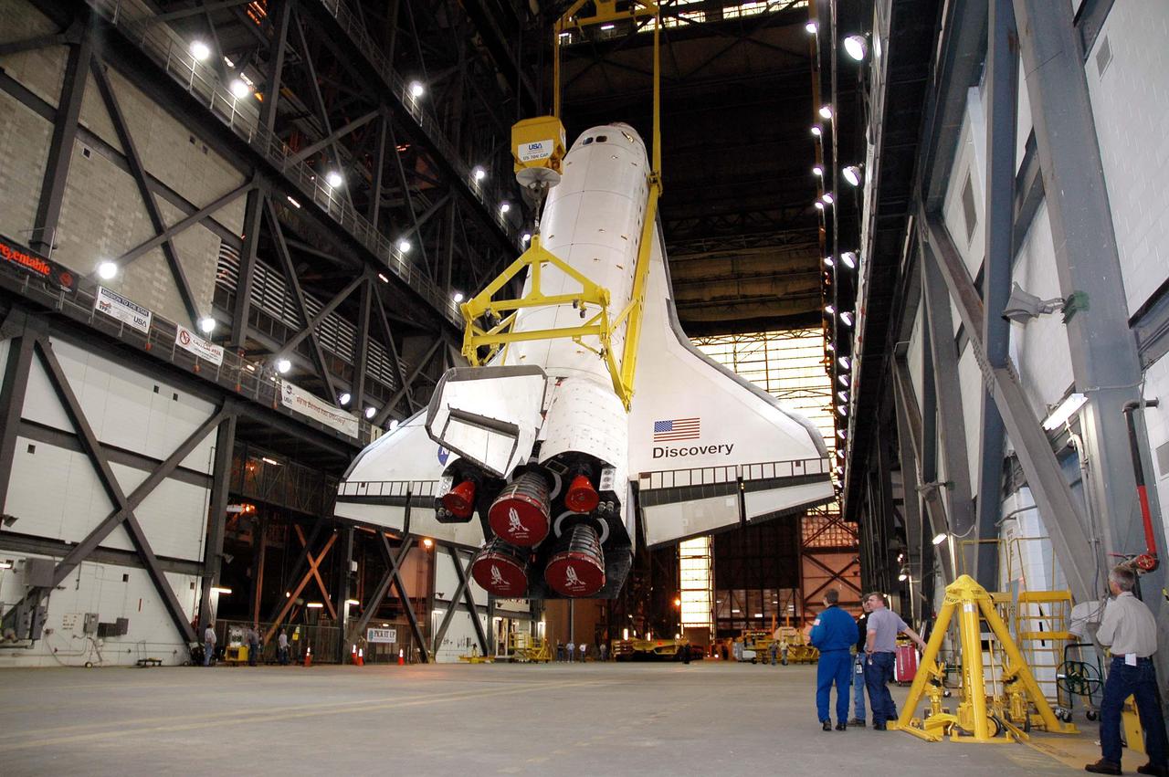 KENNEDY SPACE CENTER, FLA. - Suspended from an overhead crane, the orbiter Discovery is being lifted in the transfer aisle of the Vehicle Assembly Building at NASA’s Kennedy Space Center. Discovery will be lifted up and then lowered to the Solid Rocket Booster and External Tank already stacked on the top of the Mobile Launcher Platform (MLP). After Discovery has been mated to the External Tank_Solid Rocket Booster assembly on the MLP and all umbilicals have been connected, workers will perform an electrical and mechanical verification of the mated interfaces to verify all critical vehicle connections. A Shuttle interface test is performed using the launch processing system to verify Space Shuttle vehicle interfaces and Space Shuttle vehicle-to-ground interfaces. In approximately one week, Space Shuttle Discovery will be ready for rollout to Launch Pad 39B for Return to Flight mission STS-114. The launch window for STS-114 is May 15 to June 3.