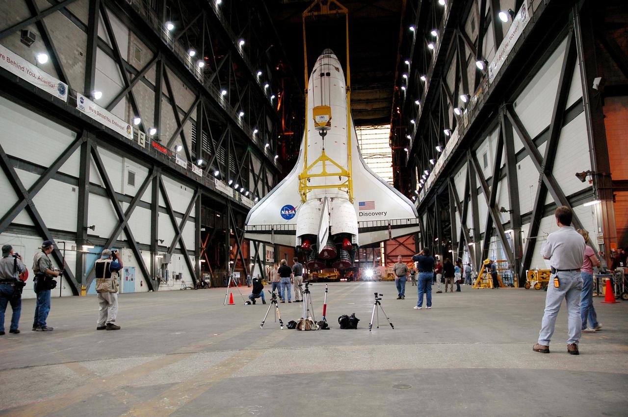 KENNEDY SPACE CENTER, FLA. - At NASA’s Kennedy Space Center, media capture the image of the orbiter Discovery as it is suspended vertically from an overhead crane in the transfer aisle of the Vehicle Assembly Building. Discovery will be lifted up and lowered to the Solid Rocket Booster and External Tank already stacked on the top of the Mobile Launcher Platform (MLP). After Discovery has been mated to the External Tank_Solid Rocket Booster assembly on the MLP and all umbilicals have been connected, workers will perform an electrical and mechanical verification of the mated interfaces to verify all critical vehicle connections. A Shuttle interface test is performed using the launch processing system to verify Space Shuttle vehicle interfaces and Space Shuttle vehicle-to-ground interfaces. In approximately one week, Space Shuttle Discovery will be ready for rollout to Launch Pad 39B for Return to Flight mission STS-114. The launch window for STS-114 is May 15 to June 3.