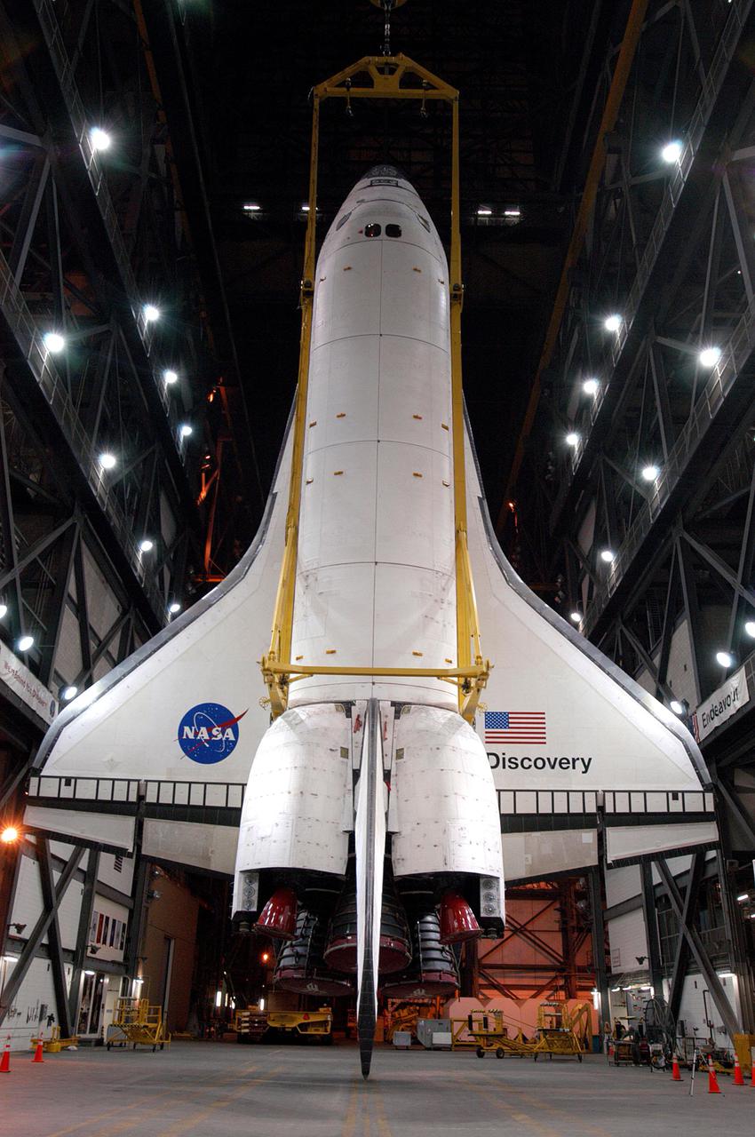 KENNEDY SPACE CENTER, FLA. - The orbiter Discovery is suspended vertically from an overhead crane in the transfer aisle of the Vehicle Assembly Building at NASA’s Kennedy Space Center. Discovery will be lifted up and lowered to the Solid Rocket Booster and External Tank already stacked on the top of the Mobile Launcher Platform (MLP). After Discovery has been mated to the External Tank_Solid Rocket Booster assembly on the MLP and all umbilicals have been connected, workers will perform an electrical and mechanical verification of the mated interfaces to verify all critical vehicle connections. A Shuttle interface test is performed using the launch processing system to verify Space Shuttle vehicle interfaces and Space Shuttle vehicle-to-ground interfaces. In approximately one week, Space Shuttle Discovery will be ready for rollout to Launch Pad 39B for Return to Flight mission STS-114. The launch window for STS-114 is May 15 to June 3.