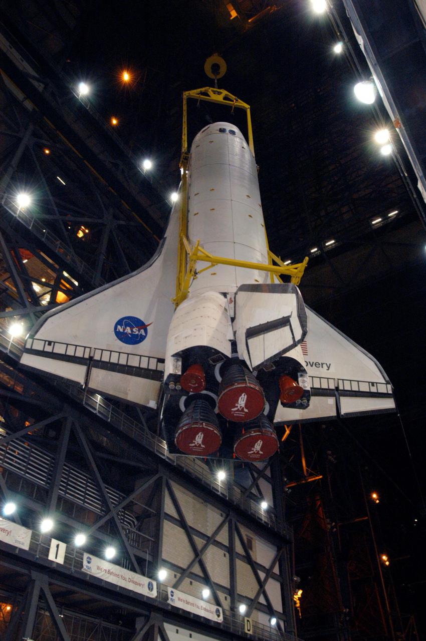 KENNEDY SPACE CENTER, FLA. - The orbiter Discovery is lifted high in the transfer aisle of the Vehicle Assembly Building at NASA’s Kennedy Space Center. Discovery will be lowered to the Solid Rocket Booster and External Tank already stacked on the top of the Mobile Launcher Platform (MLP). After Discovery has been mated to the External Tank_Solid Rocket Booster assembly on the MLP and all umbilicals have been connected, workers will perform an electrical and mechanical verification of the mated interfaces to verify all critical vehicle connections. A Shuttle interface test is performed using the launch processing system to verify Space Shuttle vehicle interfaces and Space Shuttle vehicle-to-ground interfaces. In approximately one week, Space Shuttle Discovery will be ready for rollout to Launch Pad 39B for Return to Flight mission STS-114. The launch window for STS-114 is May 15 to June 3.