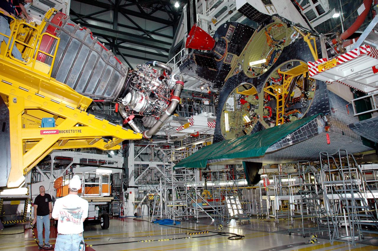 KENNEDY SPACE CENTER, FLA. -  In the Orbiter Processing Facility bay 1 at NASA’s Kennedy Space Center, a Hyster fork lift (left) holding the first Space Shuttle Main Engine (SSME) maneuvers into position number 1 (upper chamber) behind Atlantis for installation.  Overall, an SSME weighs approximately 7,000 pounds. Three engines provide the thrust, along with the two Solid Rocket Boosters, for liftoff.  After about 2 minutes, the two boosters are spent and are separated from the external tank. The SSMEs continue firing for about 8 minutes. They shut down just before the craft is inserted into orbit.  The SSMEs are tested at Stennis Space Center in Mississippi.  Atlantis is being processed for the second Return to Flight mission, STS-121, scheduled for launch in a window from July 12 through July 31.