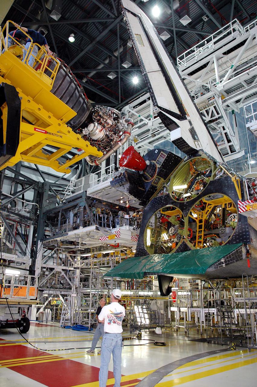 KENNEDY SPACE CENTER, FLA. -  In the Orbiter Processing Facility bay 1 at NASA’s Kennedy Space Center, a Hyster fork lift (left) holding a Space Shuttle Main Engine (SSME) maneuvers into position number 1 (upper chamber) behind Atlantis for installation.  Overall, an SSME weighs approximately 7,000 pounds. Three engines provide the thrust, along with the two Solid Rocket Boosters, for liftoff.  After about 2 minutes, the two boosters are spent and are separated from the external tank. The SSMEs continue firing for about 8 minutes. They shut down just before the craft is inserted into orbit.  The SSMEs are tested at Stennis Space Center in Mississippi.  Atlantis is being processed for the second Return to Flight mission, STS-121, scheduled for launch in a window from July 12 through July 31.