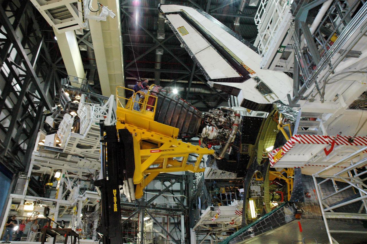 KENNEDY SPACE CENTER, FLA. -  In the Orbiter Processing Facility bay 1 at NASA’s Kennedy Space Center, a Hyster fork lift (left) holding Space Shuttle Main Engine (SSME) closes in on position number 1 for installation in Atlantis.  Overall, an SSME weighs approximately 7,000 pounds. Three engines provide the thrust, along with the two Solid Rocket Boosters, for liftoff.  After about 2 minutes, the two boosters are spent and are separated from the external tank. The SSMEs continue firing for about 8 minutes. They shut down just before the craft is inserted into orbit.  The SSMEs are tested at Stennis Space Center in Mississippi.  Atlantis is being processed for the second Return to Flight mission, STS-121, scheduled for launch in a window from July 12 through July 31.
