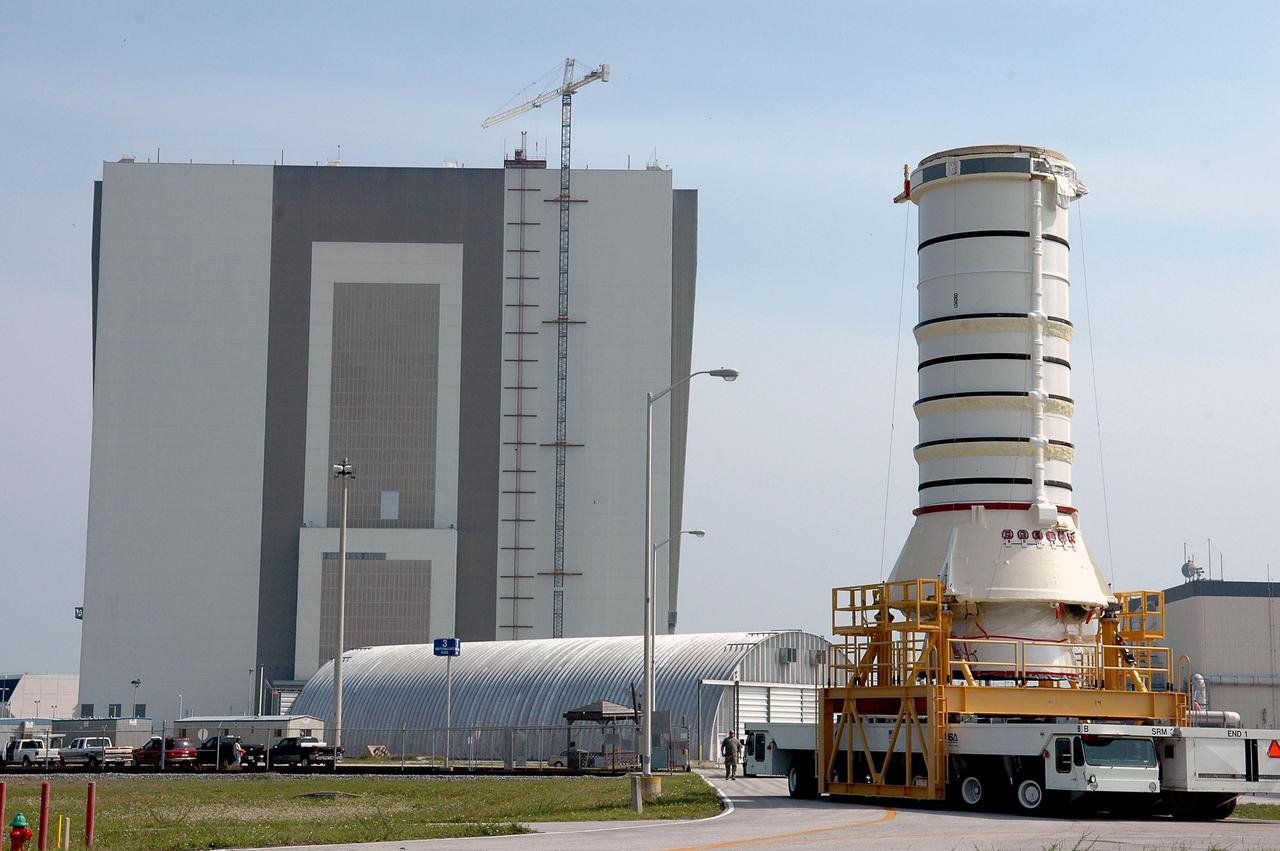 KENNEDY SPACE CENTER, FLA. - The aft segment of a Solid Rocket Booster is transported to the Vehicle Assembly Building (in the background). The segment will be mated with other segments for use on the launch of Space Shuttle Atlantis on the second Return to Flight mission, STS-121. SRBs are used as matched pairs and each is made up of four solid rocket motor segments. Two SRBs provide the main thrust to lift the Space Shuttle off the pad to an altitude of about 150,000 feet. In addition, the two SRBs carry the entire weight of the External Tank and orbiter and transmit the weight load through their structure to the Mobile Launcher Platform. Each booster has a thrust (sea level) of approximately 3,300,000 pounds at launch, and provide 71.4 percent of the thrust at liftoff and during first-stage ascent.