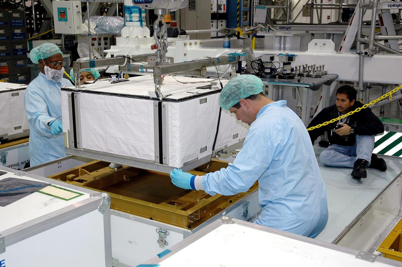 KENNEDY SPACE CENTER, FLA. -  Technicians in the Space Station Processing Facility at NASA’s Kennedy Space Center help guide one of six batteries for the P4 truss onto a stand in order to replace them.  A new battery is being installed on the truss to ensure it does not exceed the lifetime expectancy prior to installation on the International Space Station.  The P4 truss is part of the payload for mission 12A, STS-115.