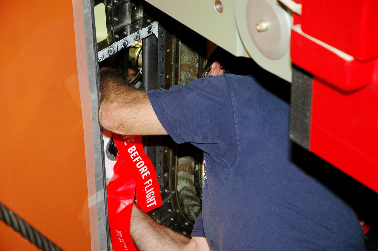 KENNEDY SPACE CENTER, FLA. - In the Vehicle Assembly Building at NASA’s Kennedy Space Center,  a worker mounts a digital still camera  in the External Tank (ET) umbilical well on the aft end of Space Shuttle Discovery.  The camera is being used to obtain and downlink high-resolution images of the disconnect point on the ET following the ET separation from the orbiter after launch. The Kodak camera will record 24 images, at one frame per 1.5 seconds, on a flash memory card. After orbital insertion, the crew will transfer the images from the memory card to a laptop computer. The files will then be downloaded through the Ku-band system to the Mission Control Center in Houston for analysis.