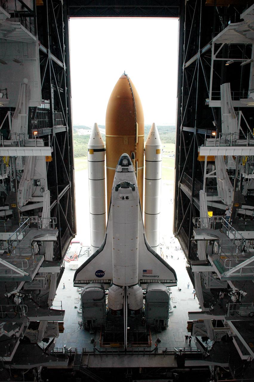KENNEDY SPACE CENTER, FLA. -  In the Vehicle Assembly Building (VAB) at NASA’s Kennedy Space Center, Space Shuttle Discovery is framed in the open doors as it begins its long, slow journey to Launch Pad 39B.  First motion was at 2:04 p.m. EDT.  The Shuttle comprises the orbiter, External Tank (ET) and twin Solid Rocket Boosters (SRBs).  The Space Shuttle rests on the Mobile Launcher Platform, which is moved by the Crawler-Transporter underneath.  The Crawler is 20 feet high, 131 feet long and 114 feet wide.  It moves on eight tracks, each containing 57 shoes, or cleats, weighing one ton each.  Loaded with the Space Shuttle, the Crawler can move at a maximum speed of approximately 1 mile an hour. A leveling system in the Crawler keeps the Shuttle vertical while negotiating the 5 percent grade leading to the top of the launch pad.  Launch of Discovery on its Return to Flight mission, STS-114, is targeted for May 15 with a launch window that extends to June 3. During its 12-day mission, Discovery’s seven-person crew will test new hardware and techniques to improve Shuttle safety, as well as deliver supplies to the International Space Station.  Discovery was moved on March 29 from the Orbiter Processing Facility to the VAB and attached to its propulsion elements, a redesigned ET and twin SRBs.