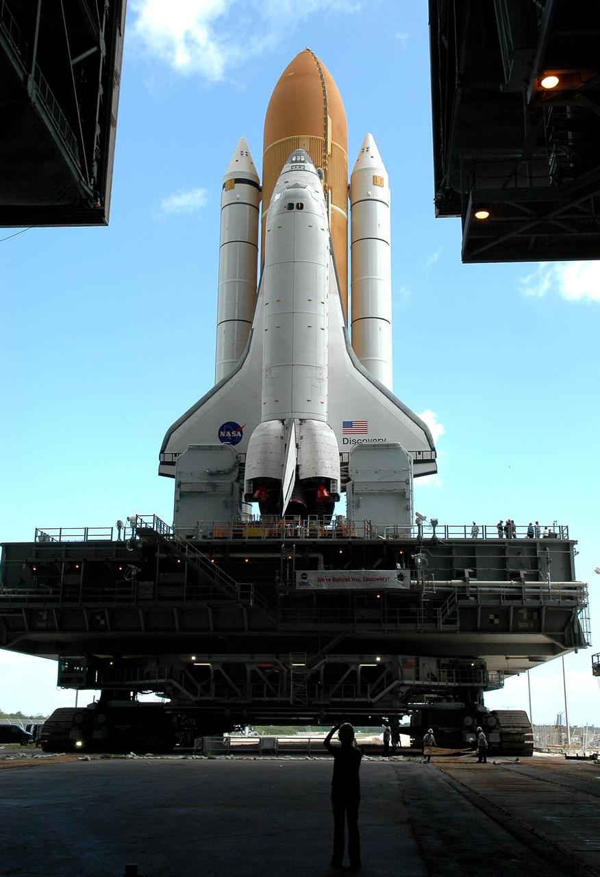 KENNEDY SPACE CENTER, FLA. -  Framed in the open doors of the Vehicle Assembly Building (VAB) at NASA’s Kennedy Space Center, Space Shuttle Discovery is bathed in light as it begins its long, slow journey to Launch Pad 39B. The Space Shuttle rests on the Mobile Launcher Platform, which is moved by the Crawler-Transporter underneath.  The Crawler is 20 feet high, 131 feet long and 114 feet wide.  It moves on eight tracks, each containing 57 shoes, or cleats, weighing one ton each.  Loaded with the Space Shuttle, the Crawler can move at a maximum speed of approximately 1 mile an hour. A leveling system in the Crawler keeps the Shuttle vertical while negotiating the 5 percent grade leading to the top of the launch pad.  Launch of Discovery on its Return to Flight mission, STS-114, is targeted for May 15 with a launch window that extends to June 3. During its 12-day mission, Discovery’s seven-person crew will test new hardware and techniques to improve Shuttle safety, as well as deliver supplies to the International Space Station.  Discovery was moved on March 29 from the Orbiter Processing Facility to the VAB and attached to its propulsion elements, a redesigned ET and twin SRBs.