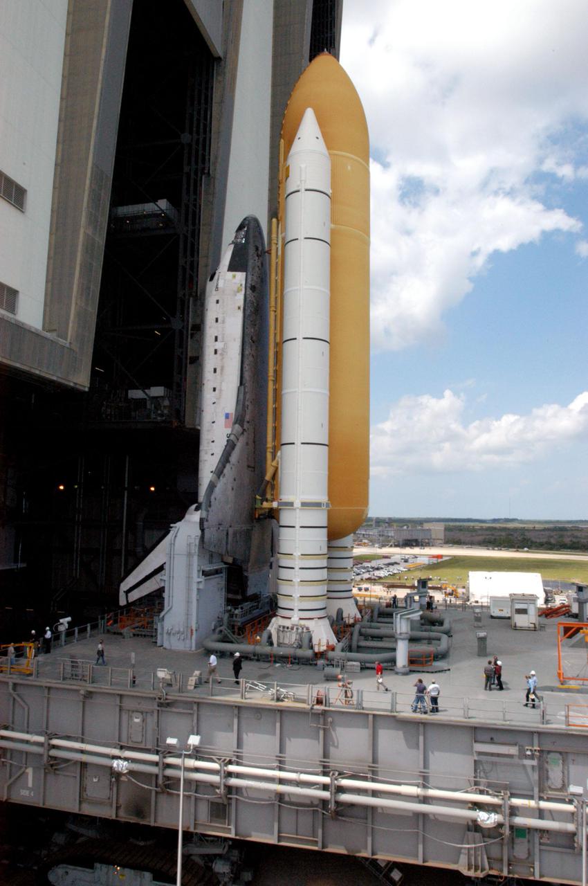 KENNEDY SPACE CENTER, FLA. -  Space Shuttle Discovery, atop the Mobile Launcher Platform, slowly rolls out of the Vehicle Assembly Building (VAB) at NASA’s Kennedy Space Center.  First motion was at 2:04 p.m. EDT.  The Shuttle comprises the orbiter, External Tank (ET) and twin Solid Rocket Boosters (SRBs).  The  Mobile Launcher Platform moved by the Crawler-Transporter underneath.  The Crawler is 20 feet high, 131 feet long and 114 feet wide.  It moves on eight tracks, each containing 57 shoes, or cleats, weighing one ton each.  Loaded with the Space Shuttle, the Crawler can move at a maximum speed of approximately 1 mile an hour. A leveling system in the Crawler keeps the Shuttle vertical while negotiating the 5 percent grade leading to the top of the launch pad.  Launch of Discovery on its Return to Flight mission, STS-114, is targeted for May 15 with a launch window that extends to June 3. During its 12-day mission, Discovery’s seven-person crew will test new hardware and techniques to improve Shuttle safety, as well as deliver supplies to the International Space Station.  Discovery was moved on March 29 from the Orbiter Processing Facility to the VAB and attached to its propulsion elements, a redesigned ET and twin SRBs.