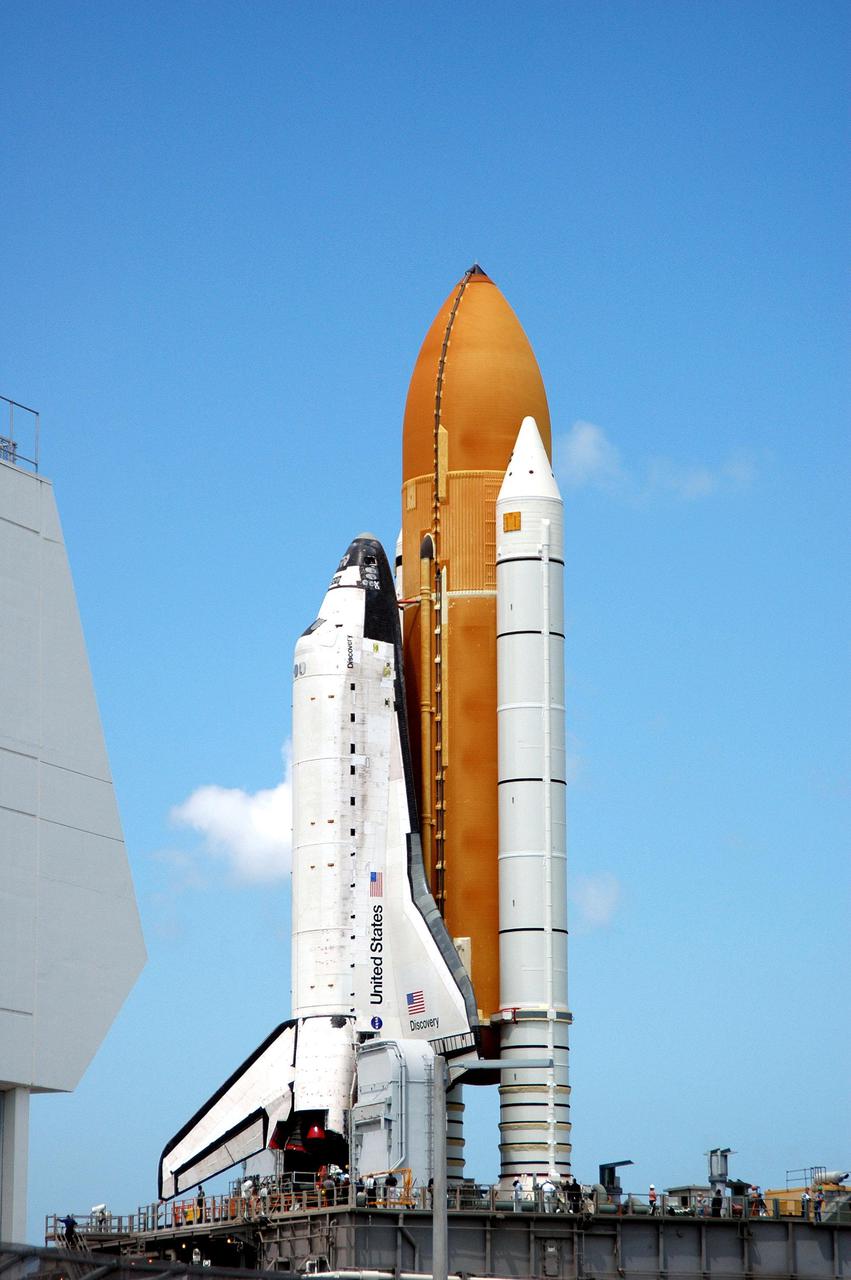 KENNEDY SPACE CENTER, FLA. -  Under brilliant-blue Florida skies, Space Shuttle Discovery, atop the Mobile Launcher Platform, wends its way slowly to Launch Pad 39B at NASA’s Kennedy Space Center.  First motion out of the Vehicle Assembly Building (VAB)  was at 2:04 p.m. EDT.  The Mobile Launcher Platform is moved by the Crawler-Transporter underneath.  The Crawler is 20 feet high, 131 feet long and 114 feet wide.  It moves on eight tracks, each containing 57 shoes, or cleats, weighing one ton each.  Loaded with the Space Shuttle, the Crawler can move at a maximum speed of approximately 1 mile an hour. A leveling system in the Crawler keeps the Shuttle vertical while negotiating the 5 percent grade leading to the top of the launch pad.  Launch of Discovery on its Return to Flight mission, STS-114, is targeted for May 15 with a launch window that extends to June 3. During its 12-day mission, Discovery’s seven-person crew will test new hardware and techniques to improve Shuttle safety, as well as deliver supplies to the International Space Station.  Discovery was moved on March 29 from the Orbiter Processing Facility to the VAB and attached to its propulsion elements, a redesigned ET and twin SRBs.